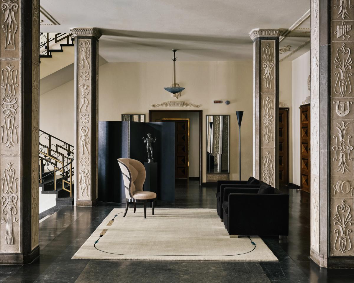 Grace 02 – Tassel — im Stockholmer Konzerthaus inszeniert. Ein handgewebter cremefarbener Teppich mit dezenten Quasten-inspirierten Linien, kombiniert mit skulpturalen Möbeln und neoklassischen Details.