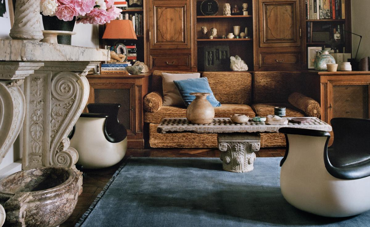 The Mohair rug in Slate Blue is shown in a Paris living room with wooden paneling, sculptural armchairs, and a marble fireplace adorned with pink flowers, creating a refined and artistic atmosphere.