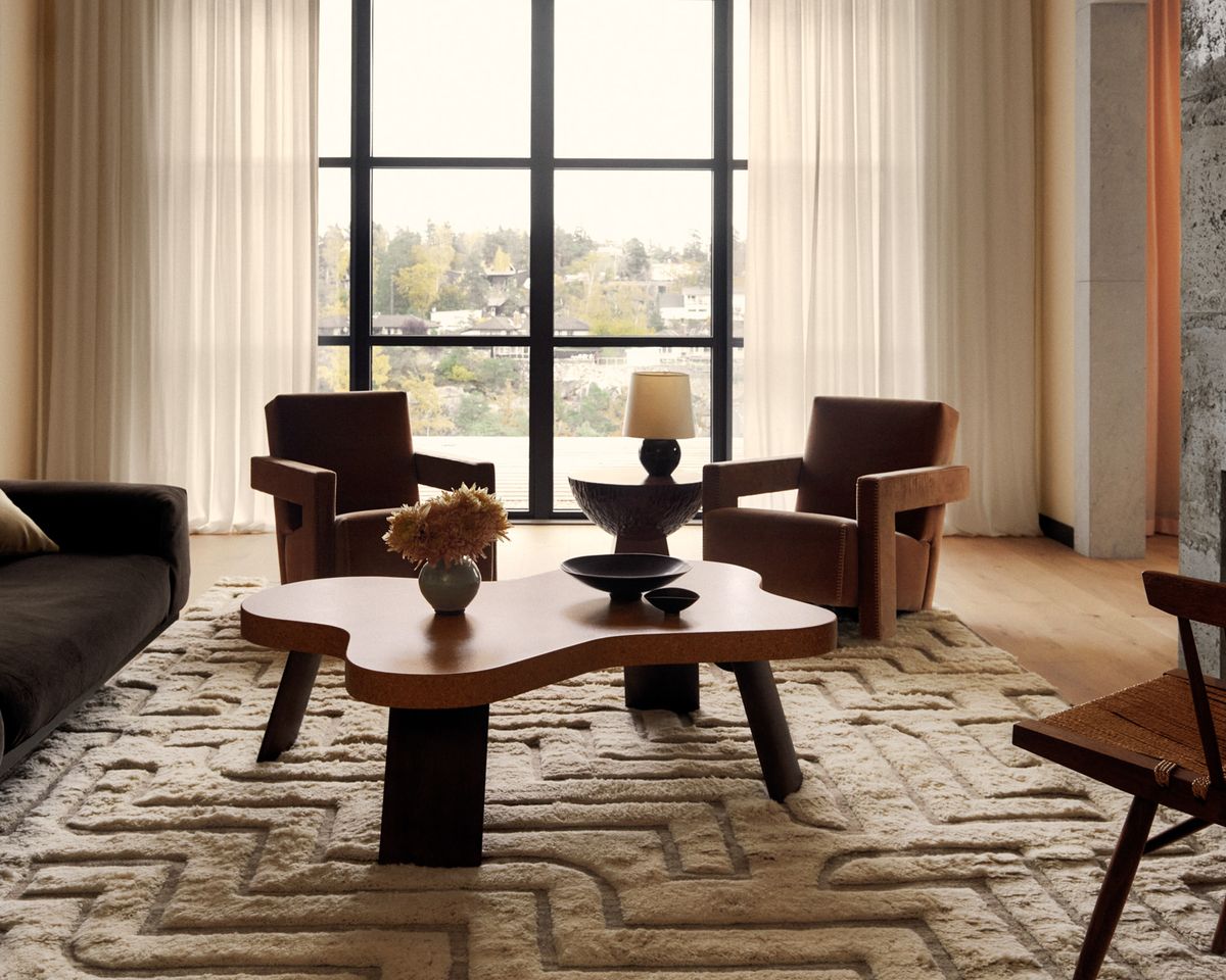 Boho 02 en Shearling, photographié dans un salon lumineux, sous une table basse sculpturale et des fauteuils près d’une grande fenêtre.