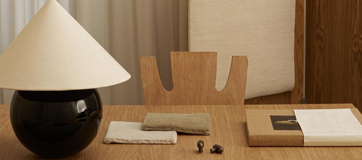 Rug samples displayed on a wooden desk with lamp and book.
