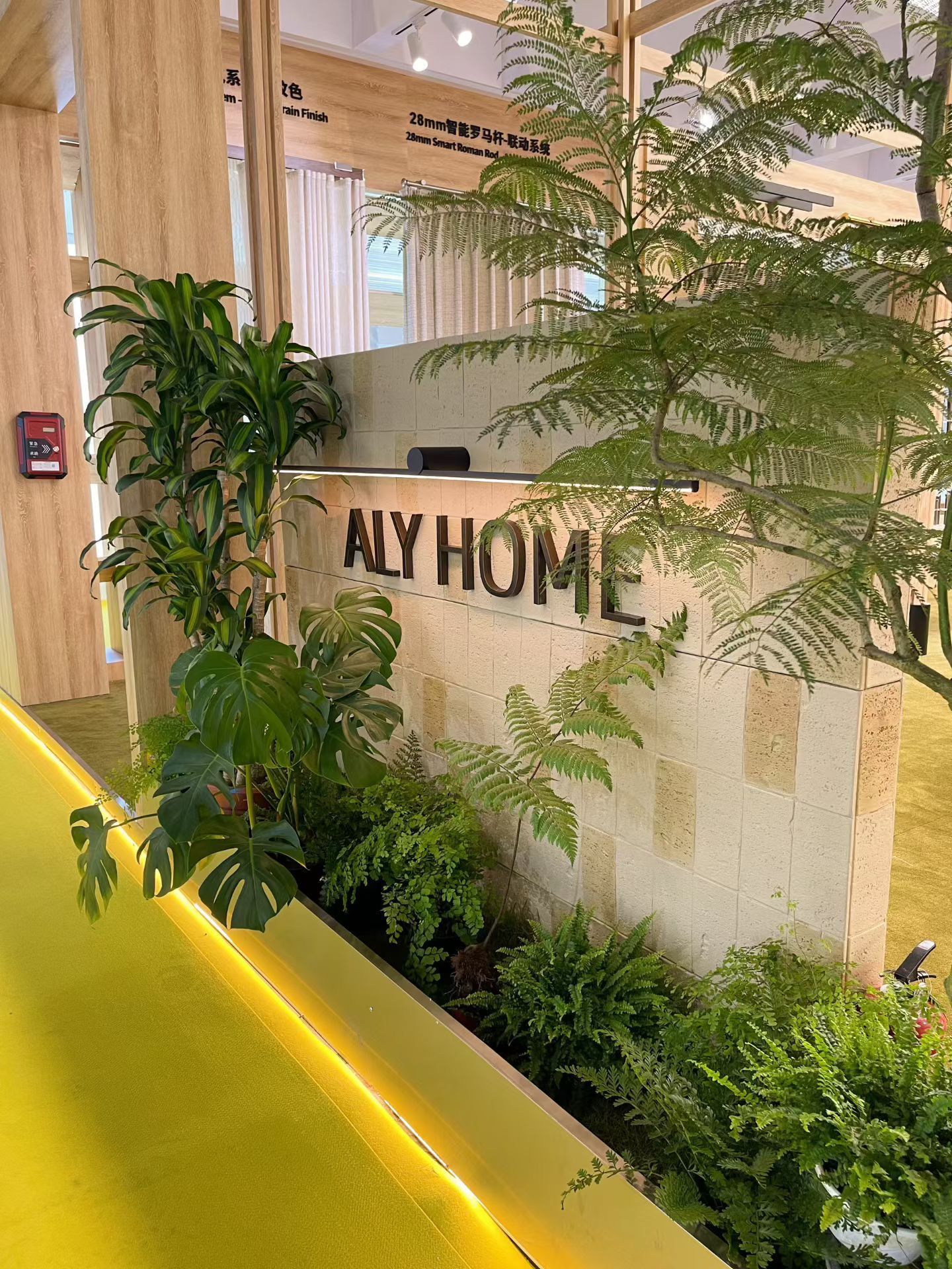 ALY HOME reception area with greenery, stone wall, and Roman rod showcase at R+T Asia 2025