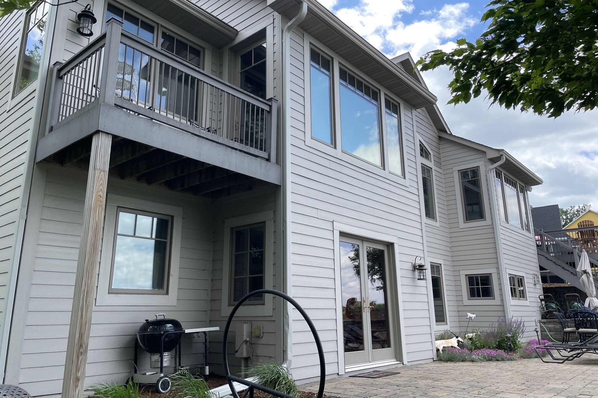 Gray-sided lakeside home exterior with balcony, French doors, paver patio and lavender plantings in Prior Lake, MN - Mom's Design Build