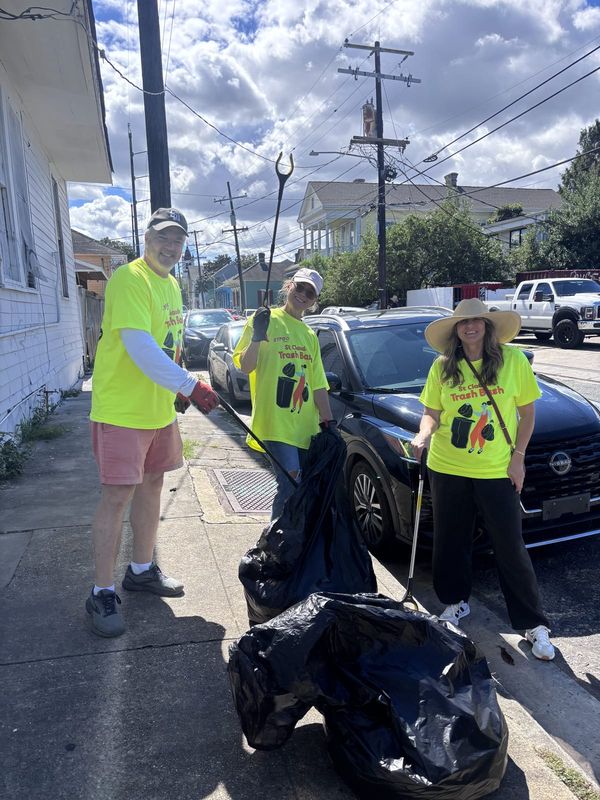 Three volunteers with grabbers and full trash bags on a Bywater sidewalk