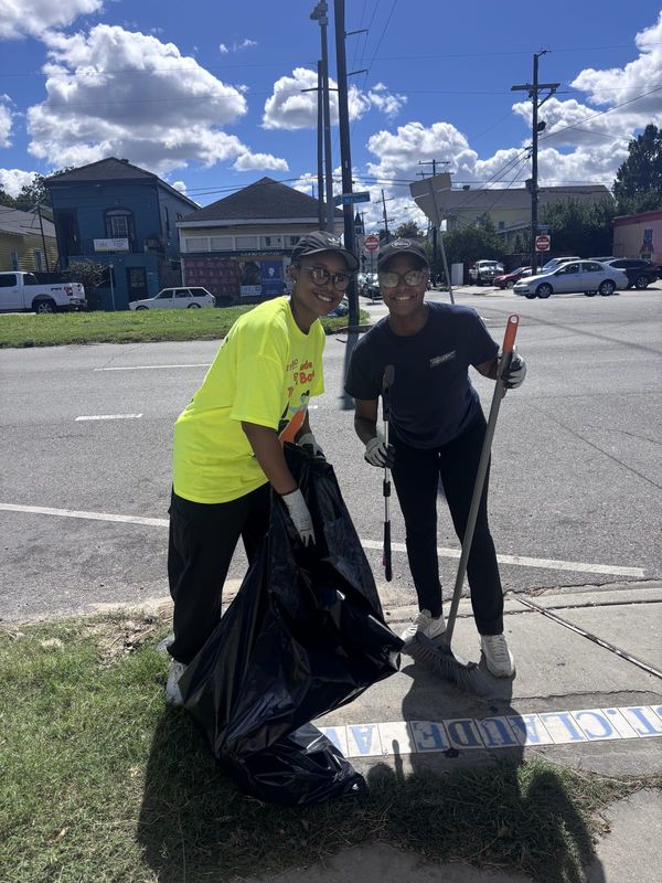 Two volunteers with trash bags and grabbers at a St. Claude corner