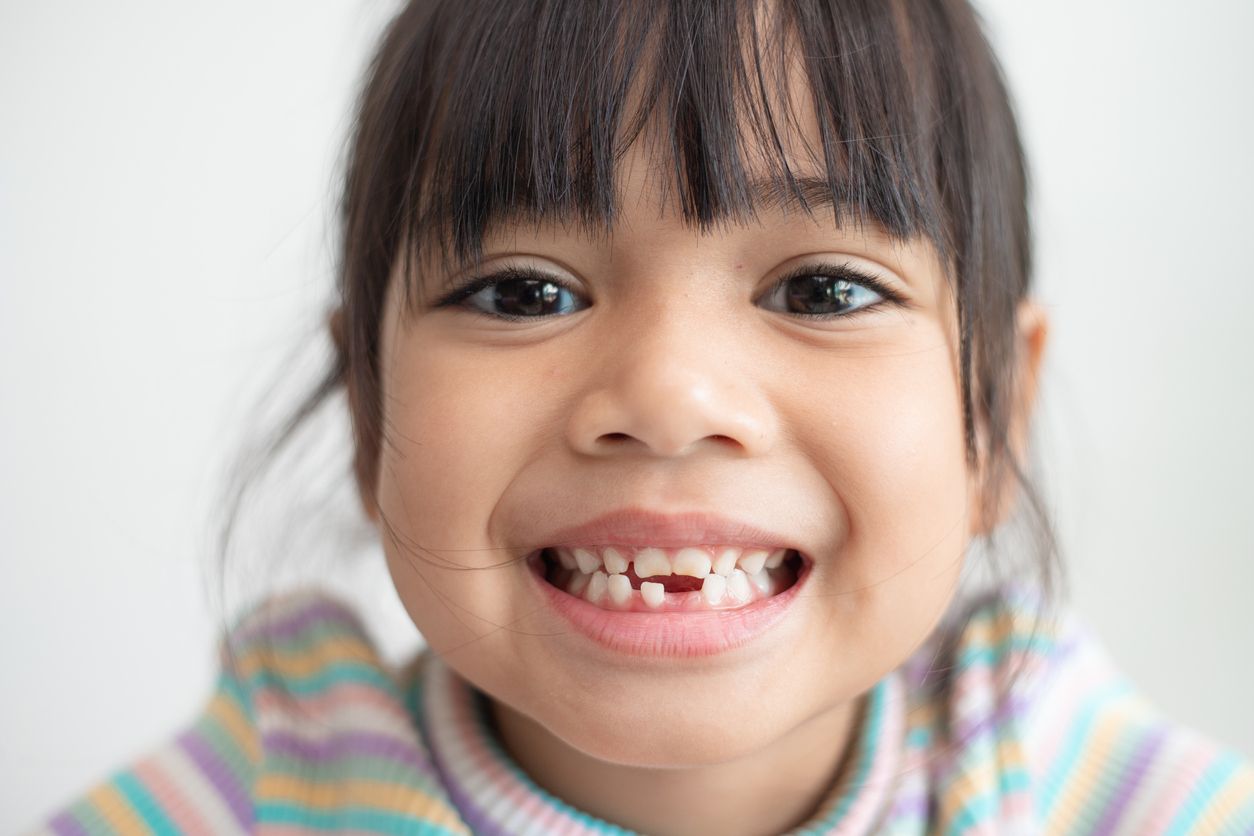 Cute young girl grinning showing she has lost a baby tooth