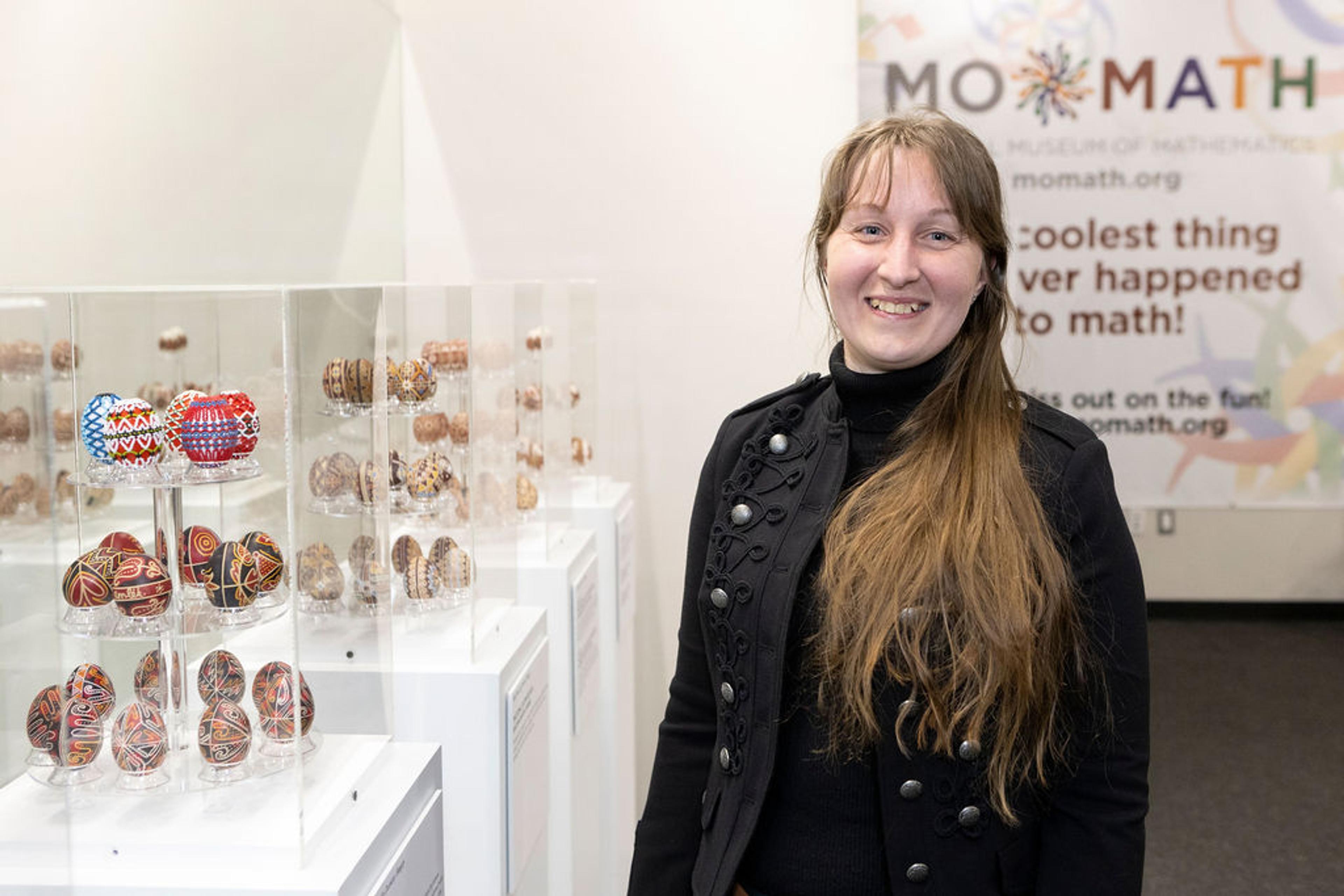 woman standing next to decorated eggs at an exhibit