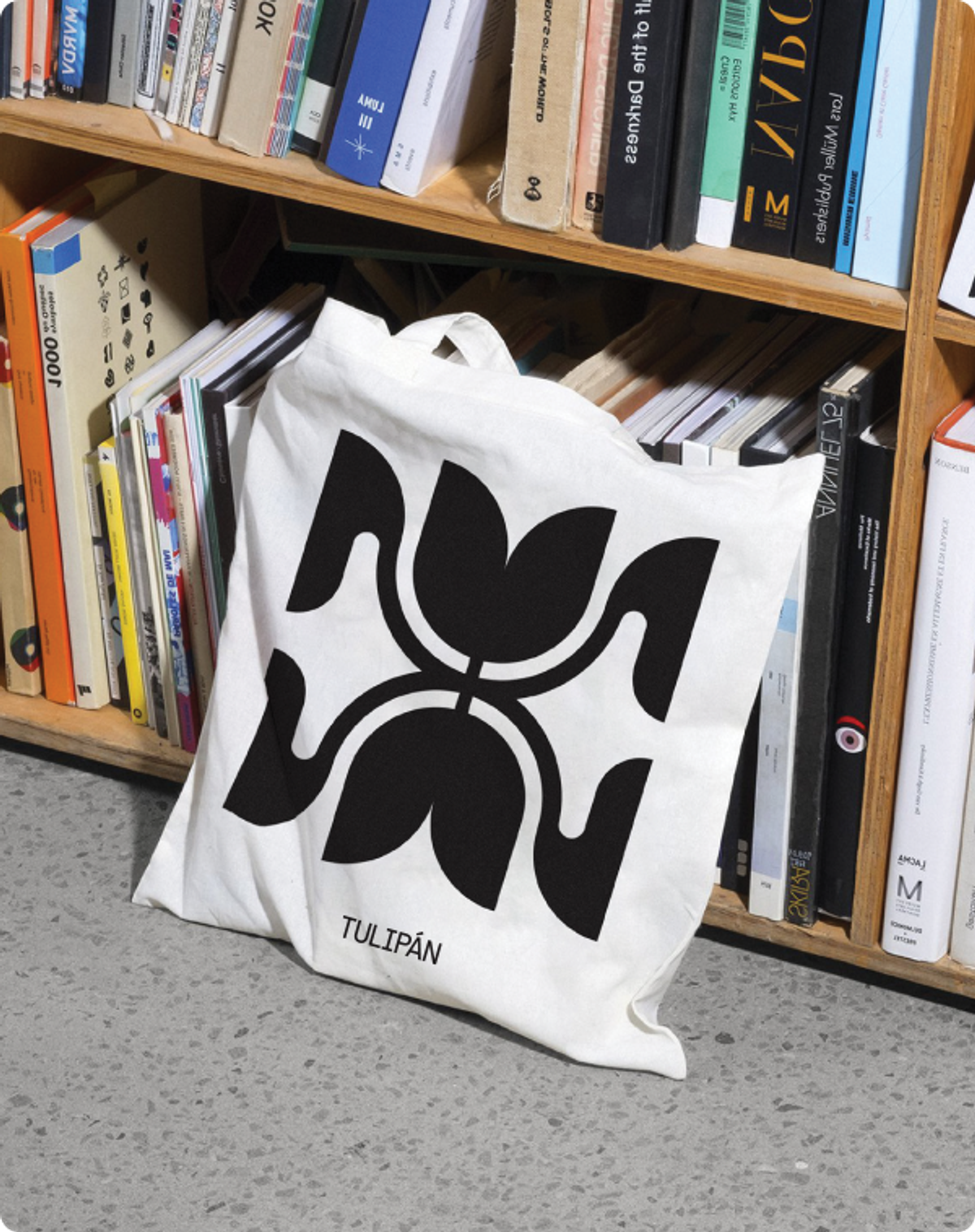 tulipan logo on a tote bag in front a bookcase