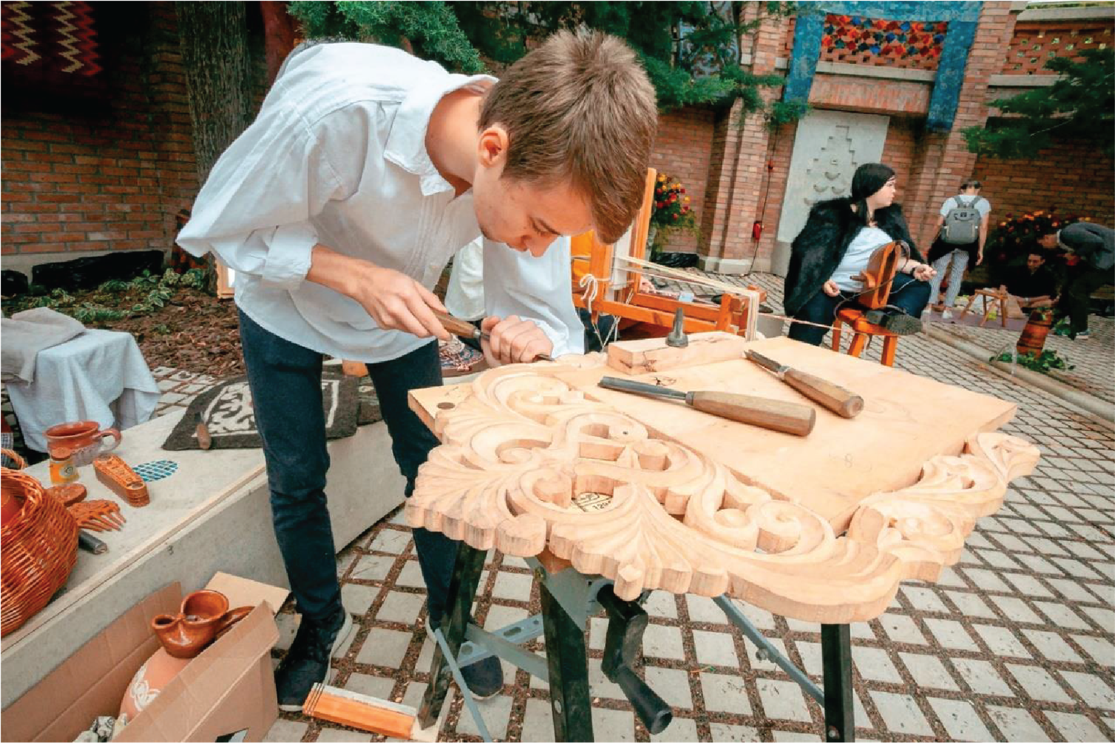 young man hand carving a wood frame