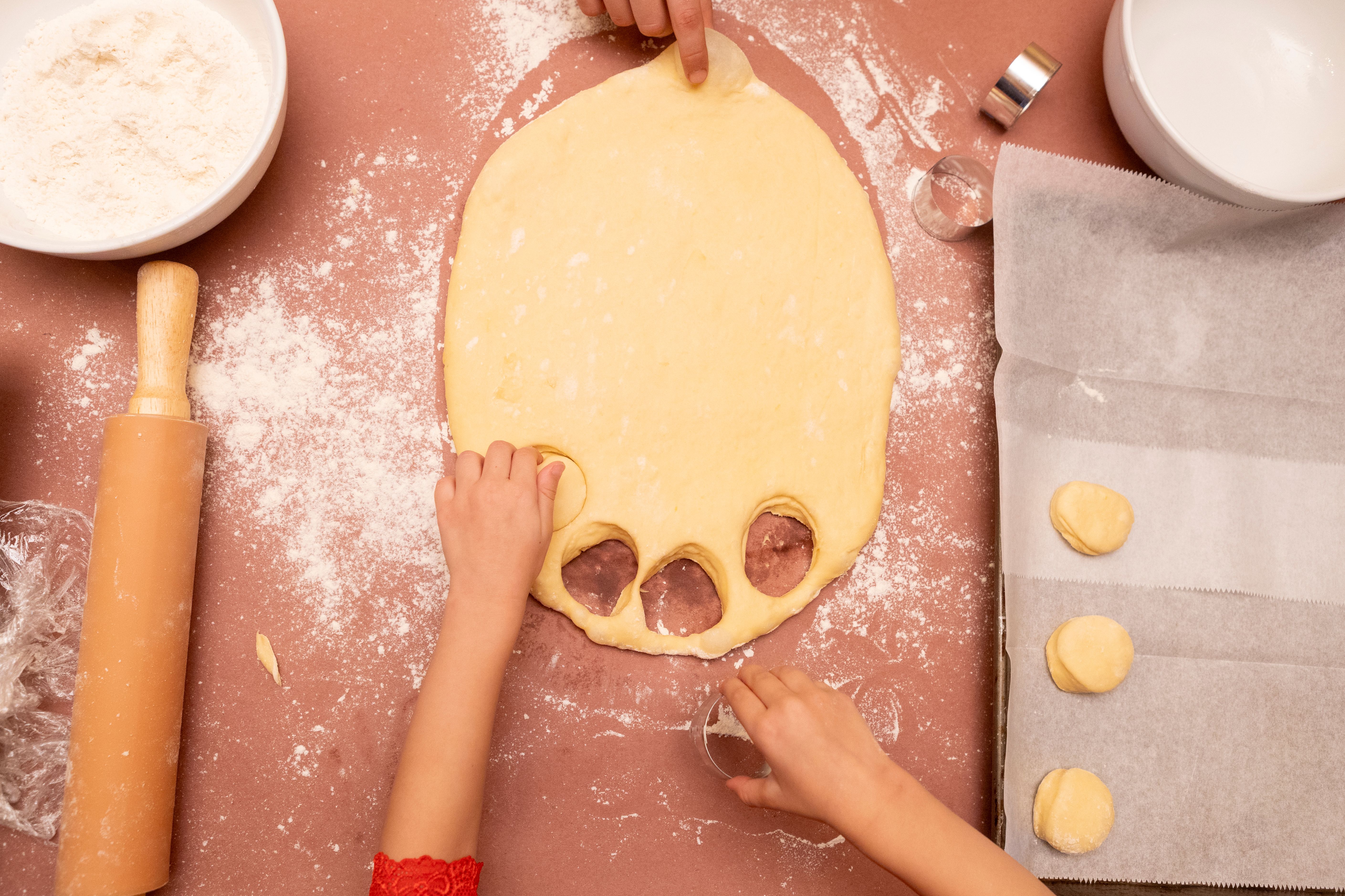 child cutting out donuts from dough