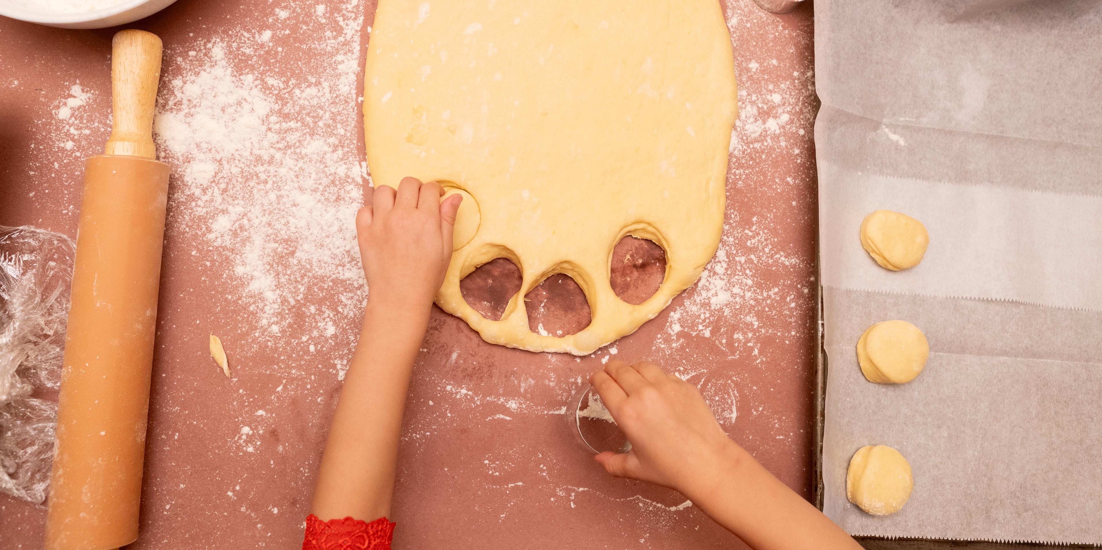 child cutting out donuts from dough