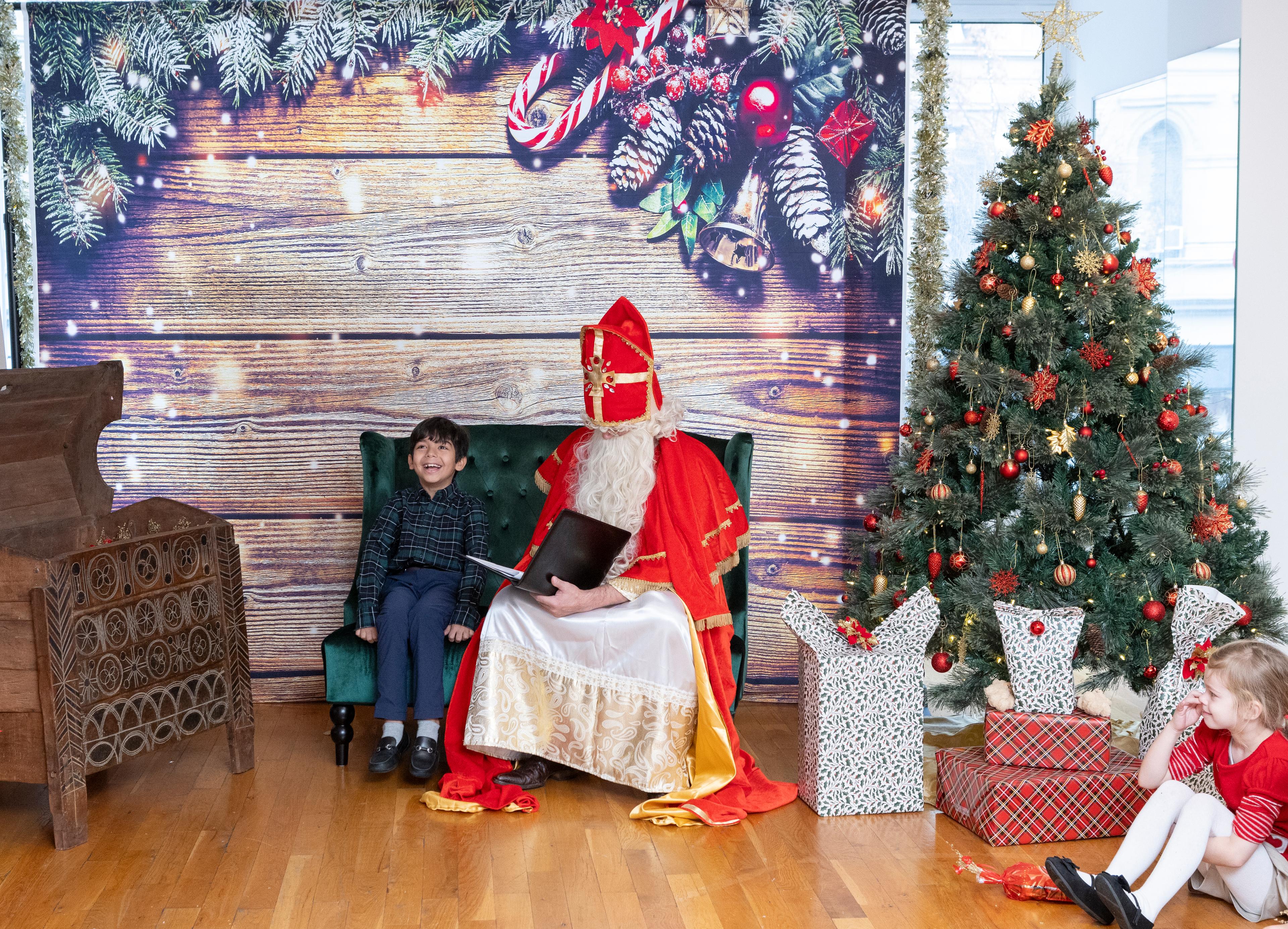 little boy sitting on a decorated bench next to santa claus