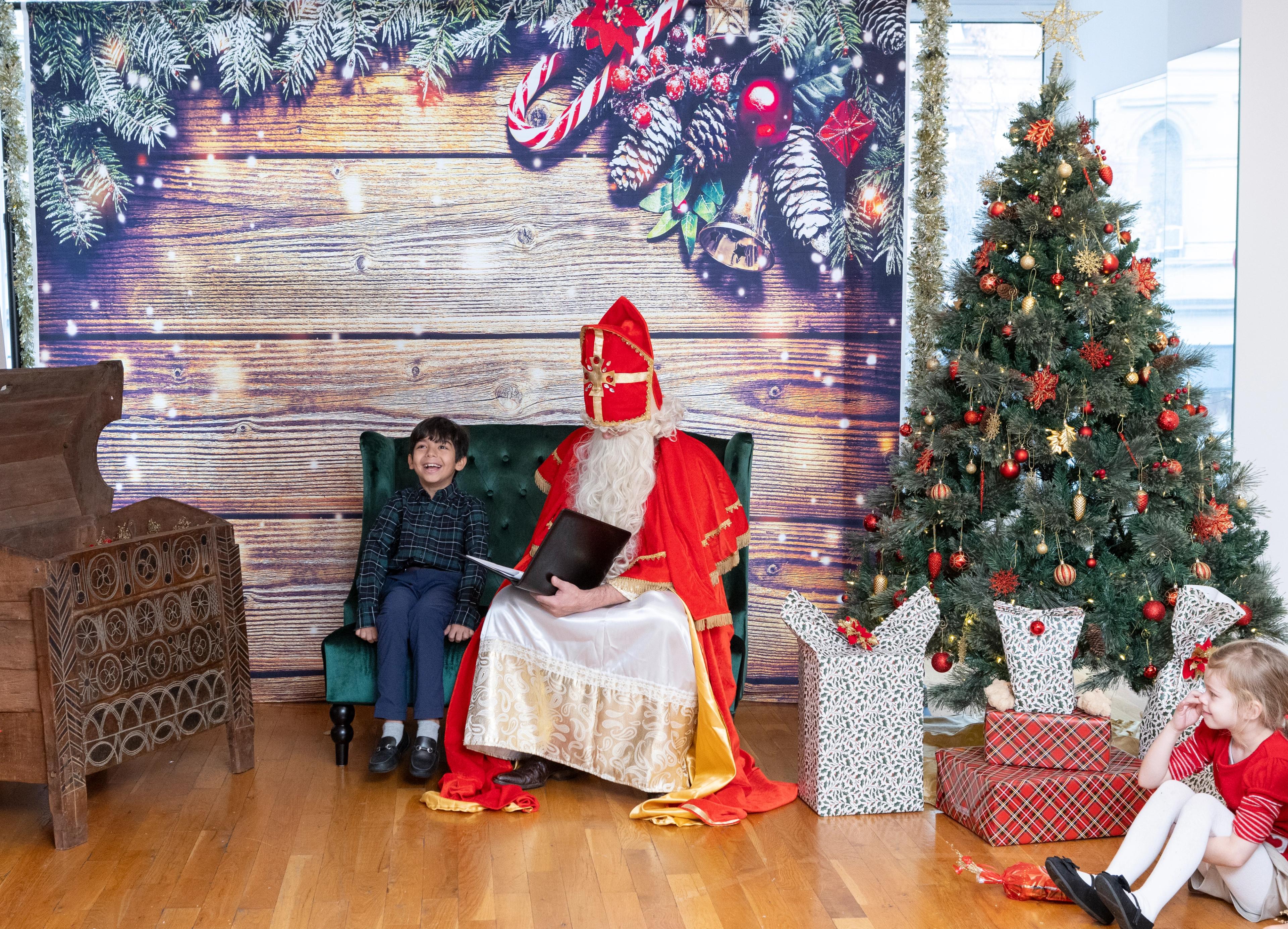 little boy sitting on a decorated bench next to santa claus