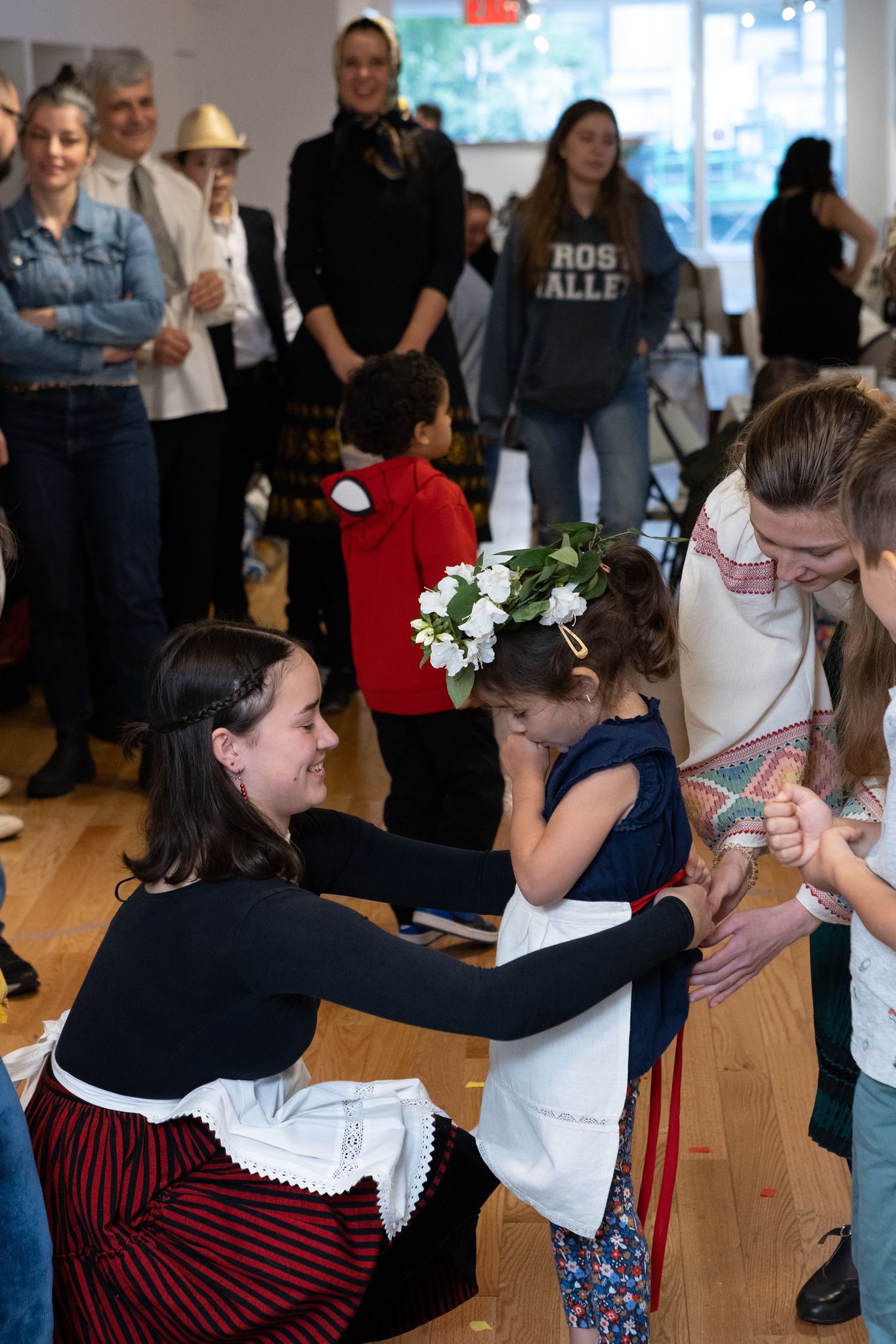 woman wrapping an apron on a little girl with flowers on her head