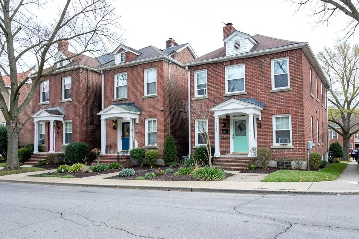 Brick two-family homes with small front gardens on a residential street in Pelham Bay, Bronx, NY