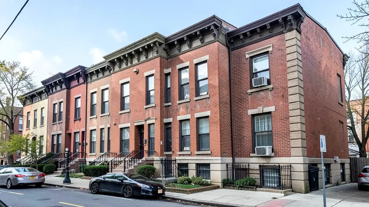 Attached brick rowhouses with cornices along a residential street in Ridgewood, Queens, NY