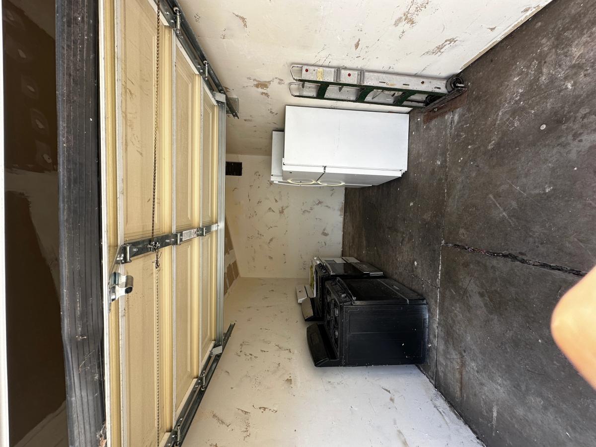 Unfinished garage interior with bare walls and disconnected appliances before the ADU conversion