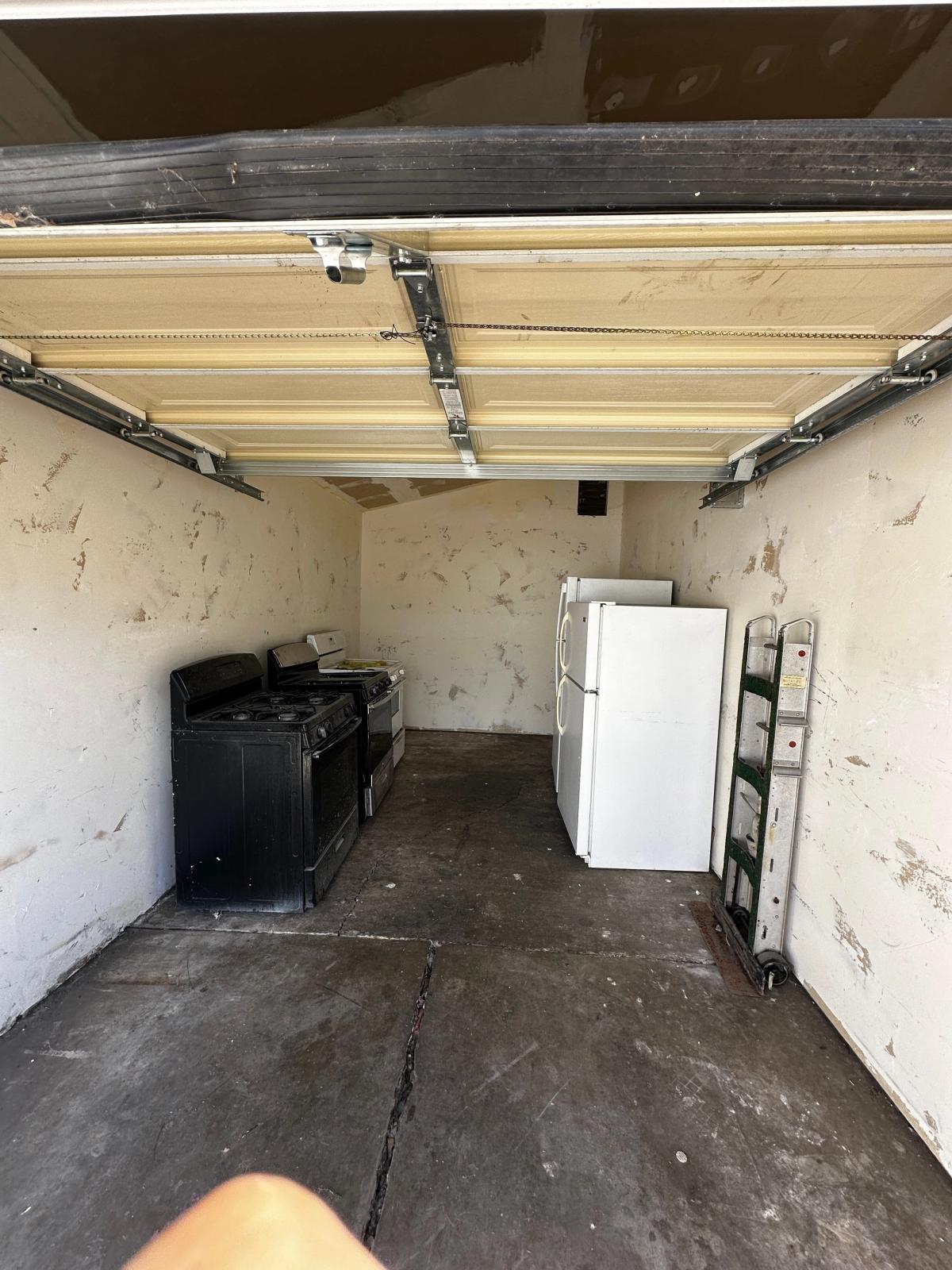 Unfinished garage interior with bare walls and disconnected appliances before the ADU conversion