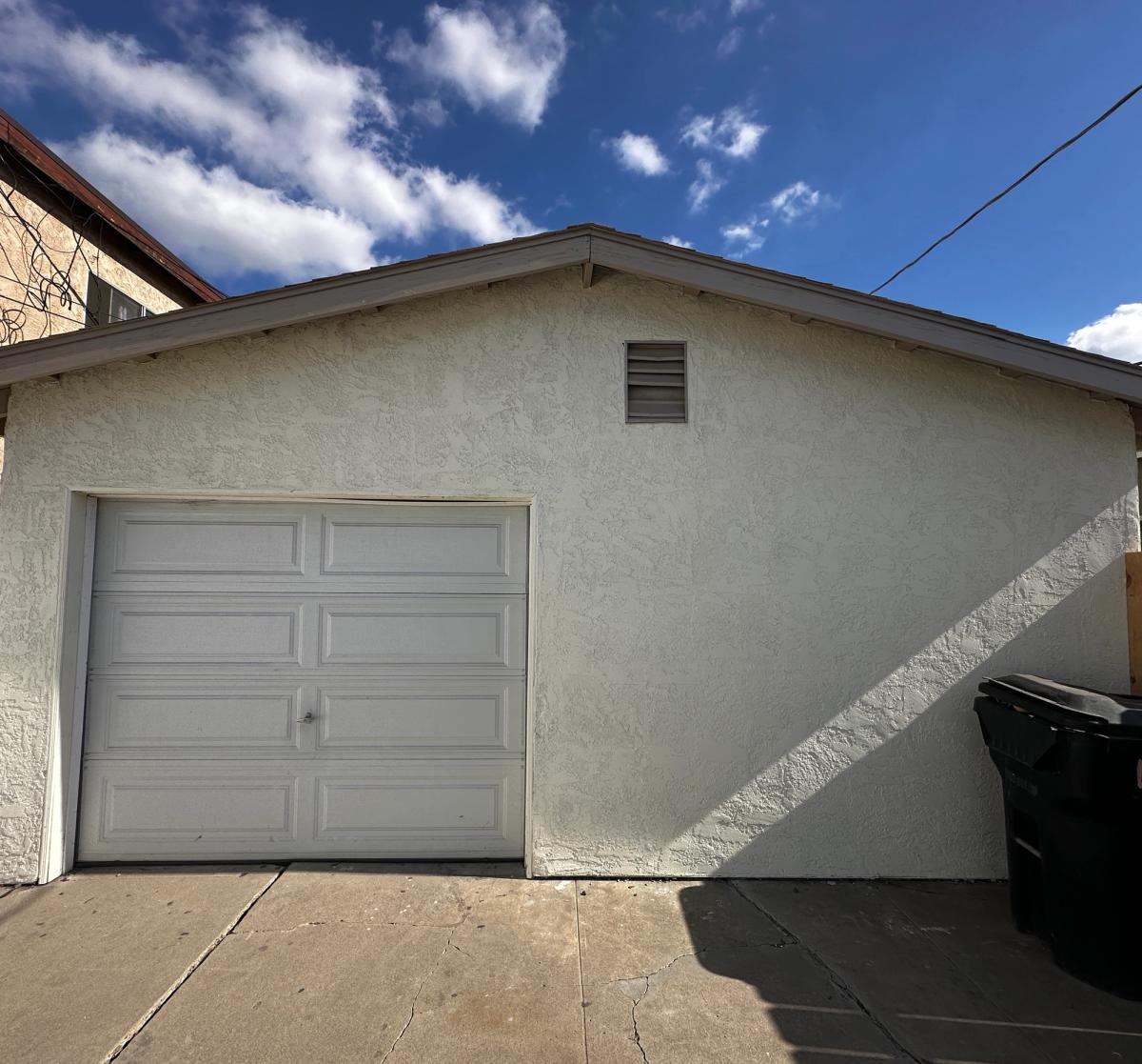 Single-car garage with a white roll-up door before its conversion to an ADU in San Diego