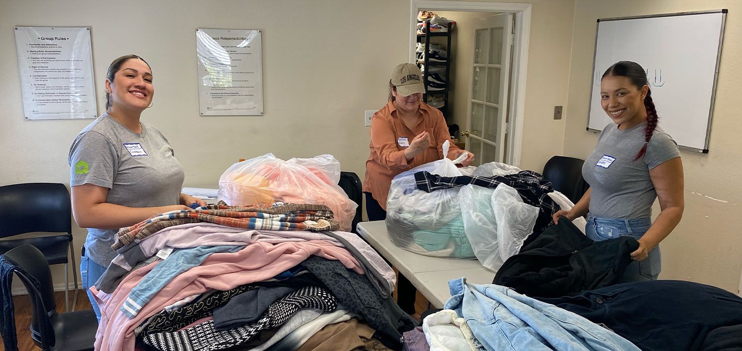 Volunteers from Invitation Homes helping sort donated clothes for the clients.