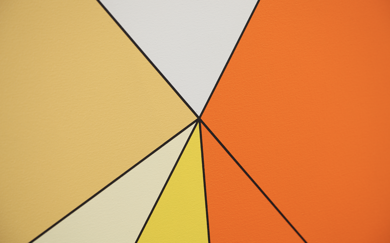 Detail of painting with yellow, white and orange triangles in acrylic paint meeting at a point