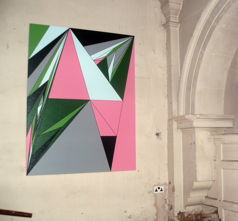 Painting of green, pink and light blue triangles displayed on plastered wall with a section of an arch on the right