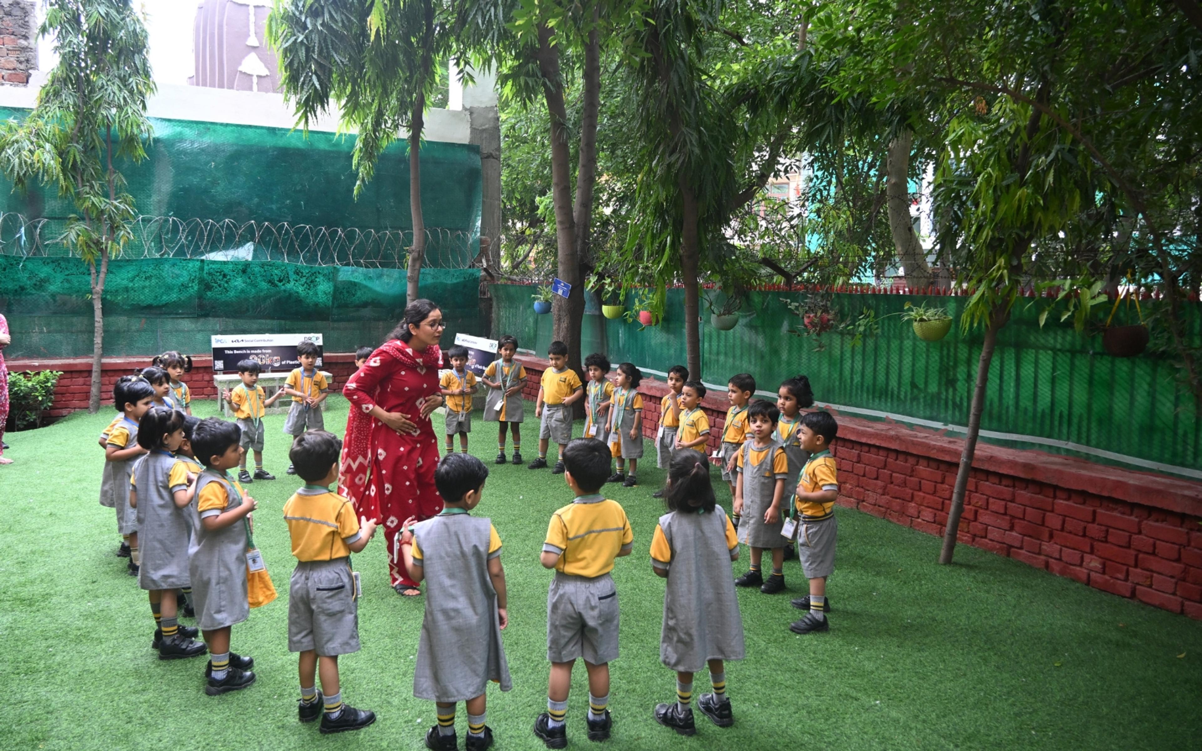 A teacher leading children through an outdoor group exercise