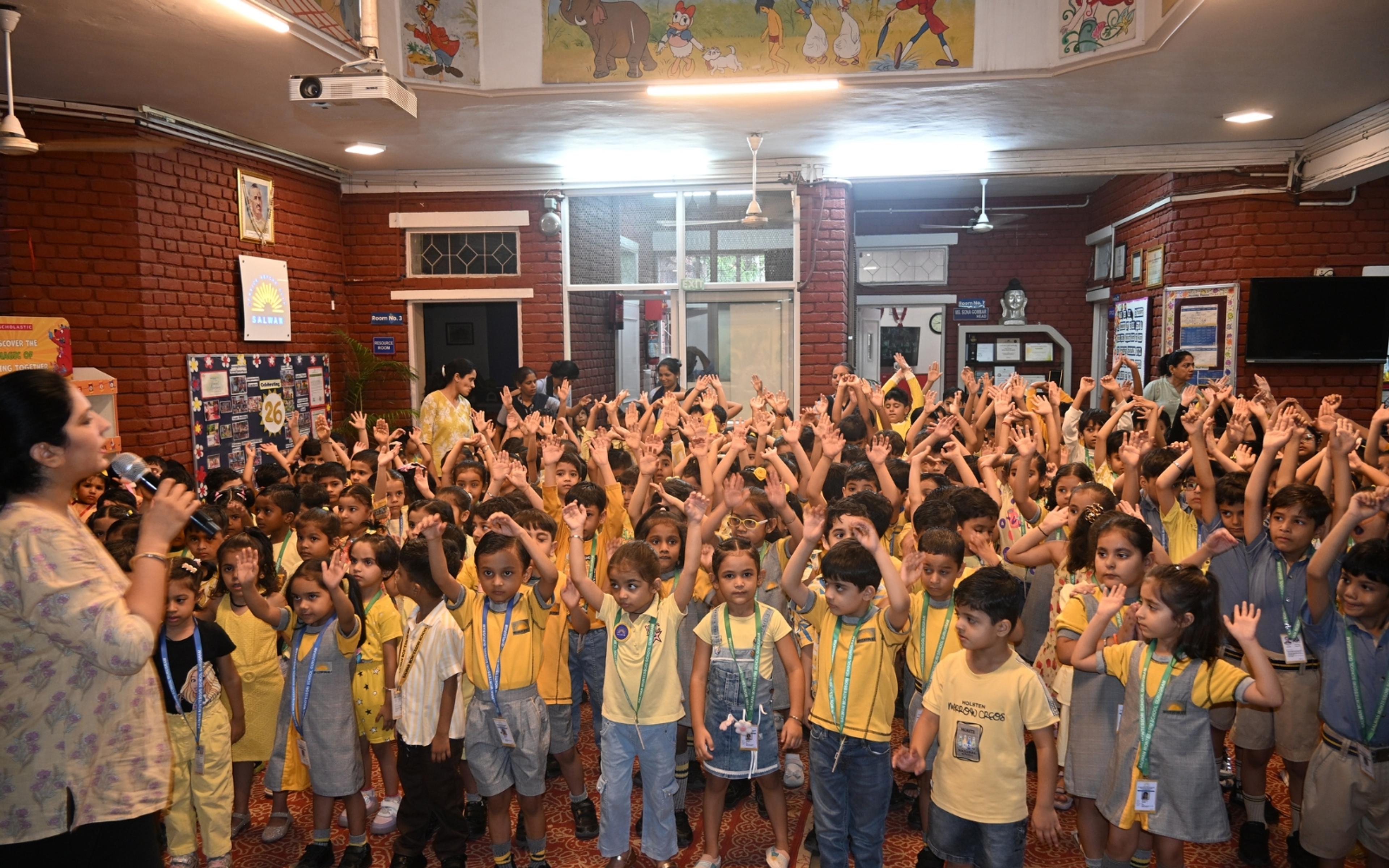 The school community raising their hands during an indoor gathering