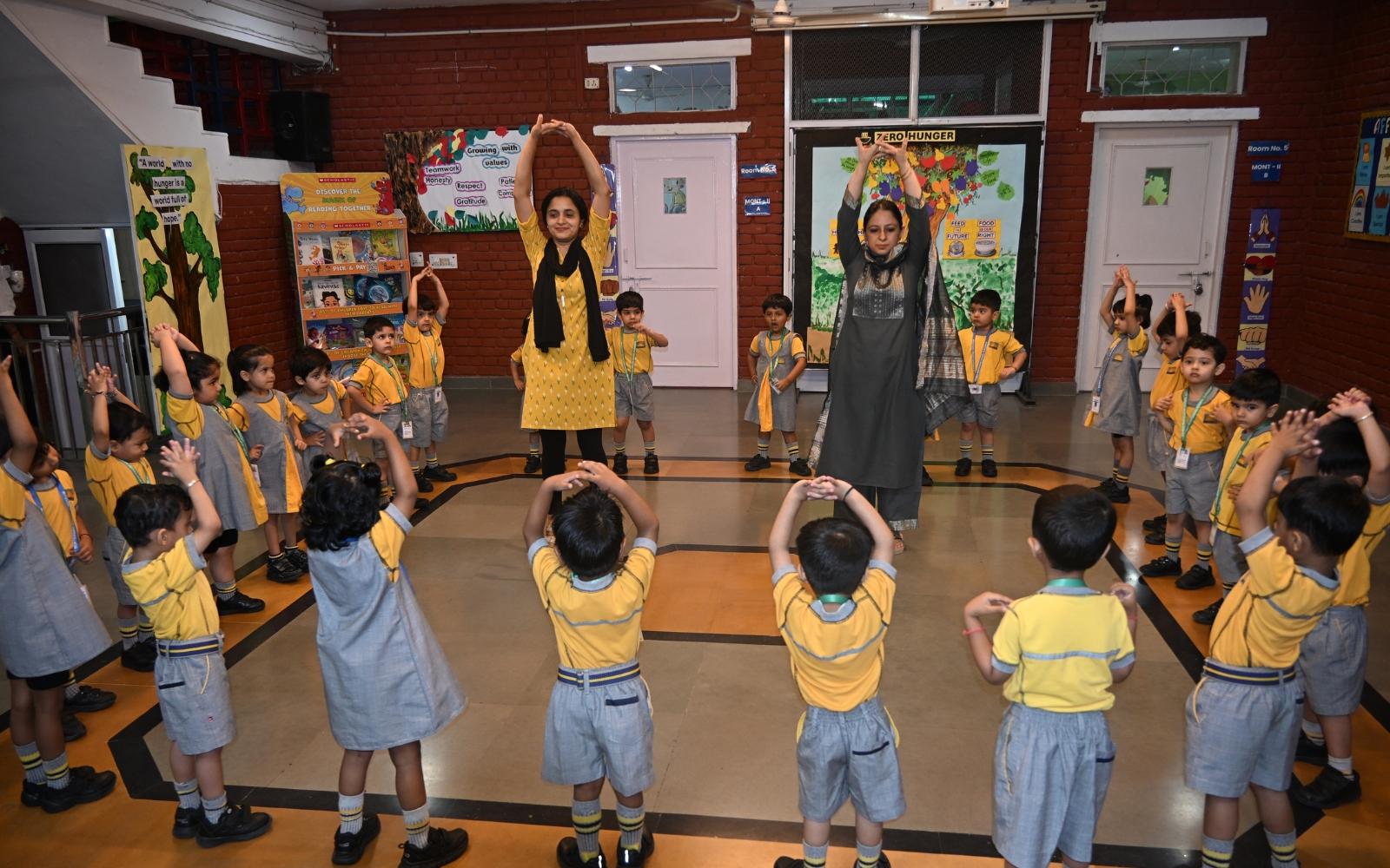 Teachers leading children through a group movement activity