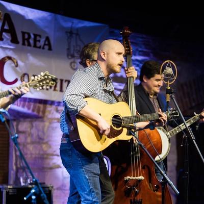 Missouri Fury performing on stage at a community event, with guitar, banjo, and upright bass.