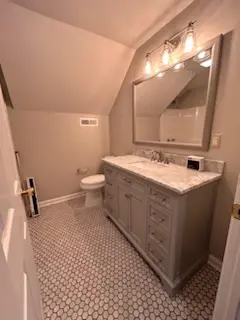 A bathroom renovation featuring a grey vanity with a marble countertop and a grey hexagon tile floor