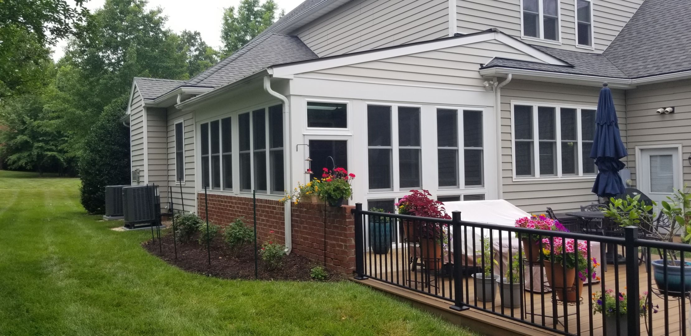 A house with a sunroom featuring large windows extending from the main structure