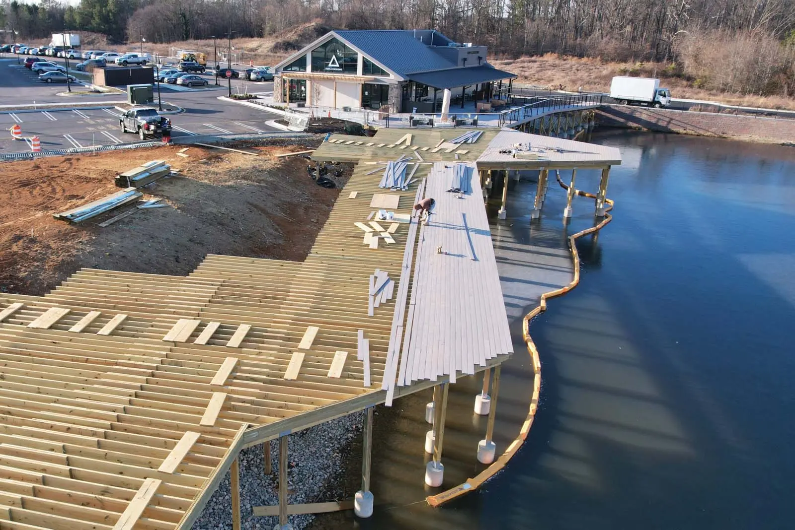 large deck in progress for Triple Crossing Brewery and Wong's Tacos at the Winterfield Crossing shopping plaza, extending over the pond