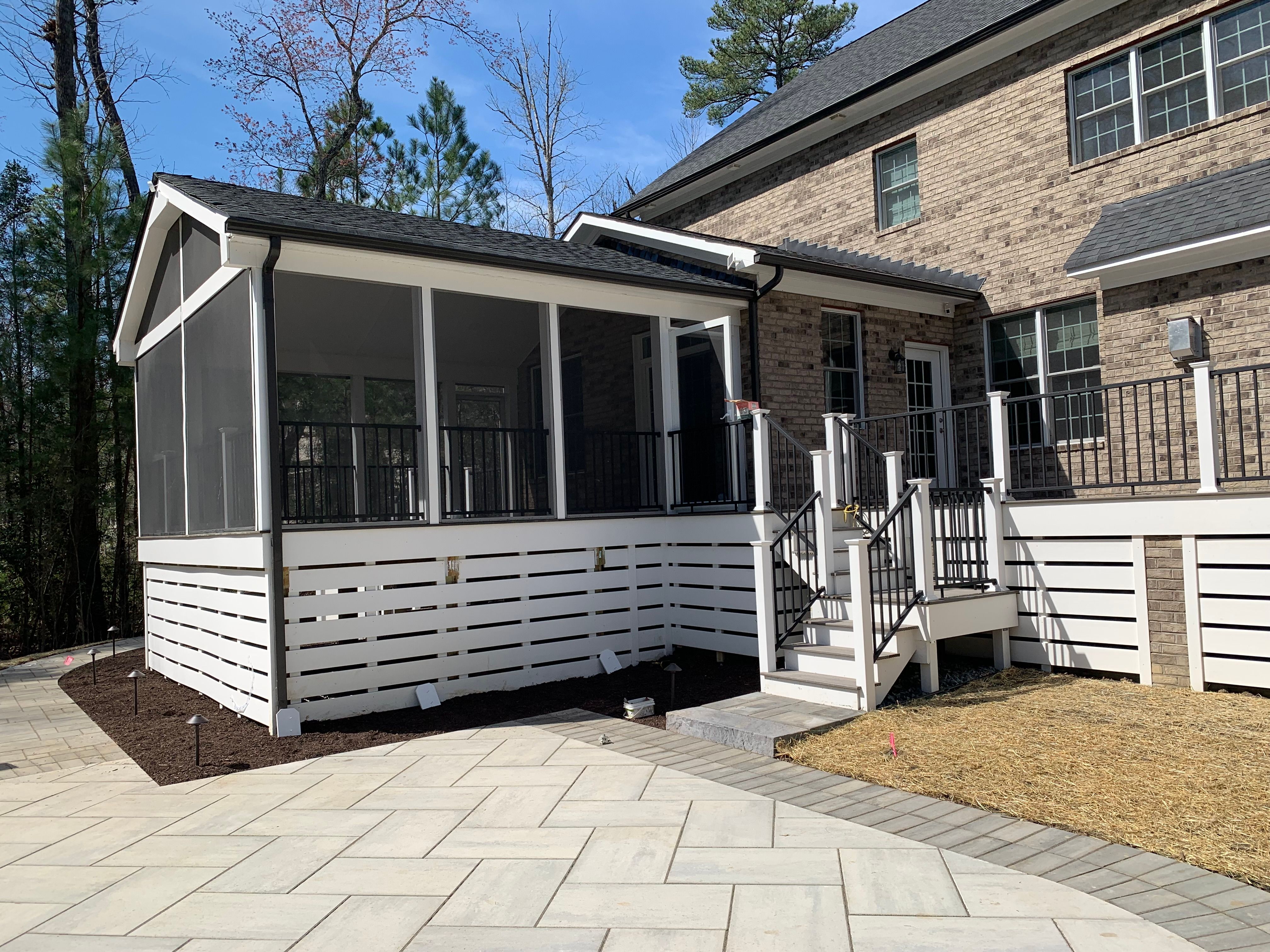 Large screen porch with deck made of Trex Coastal Bluff and stairs leading to back yard with a large stone patio