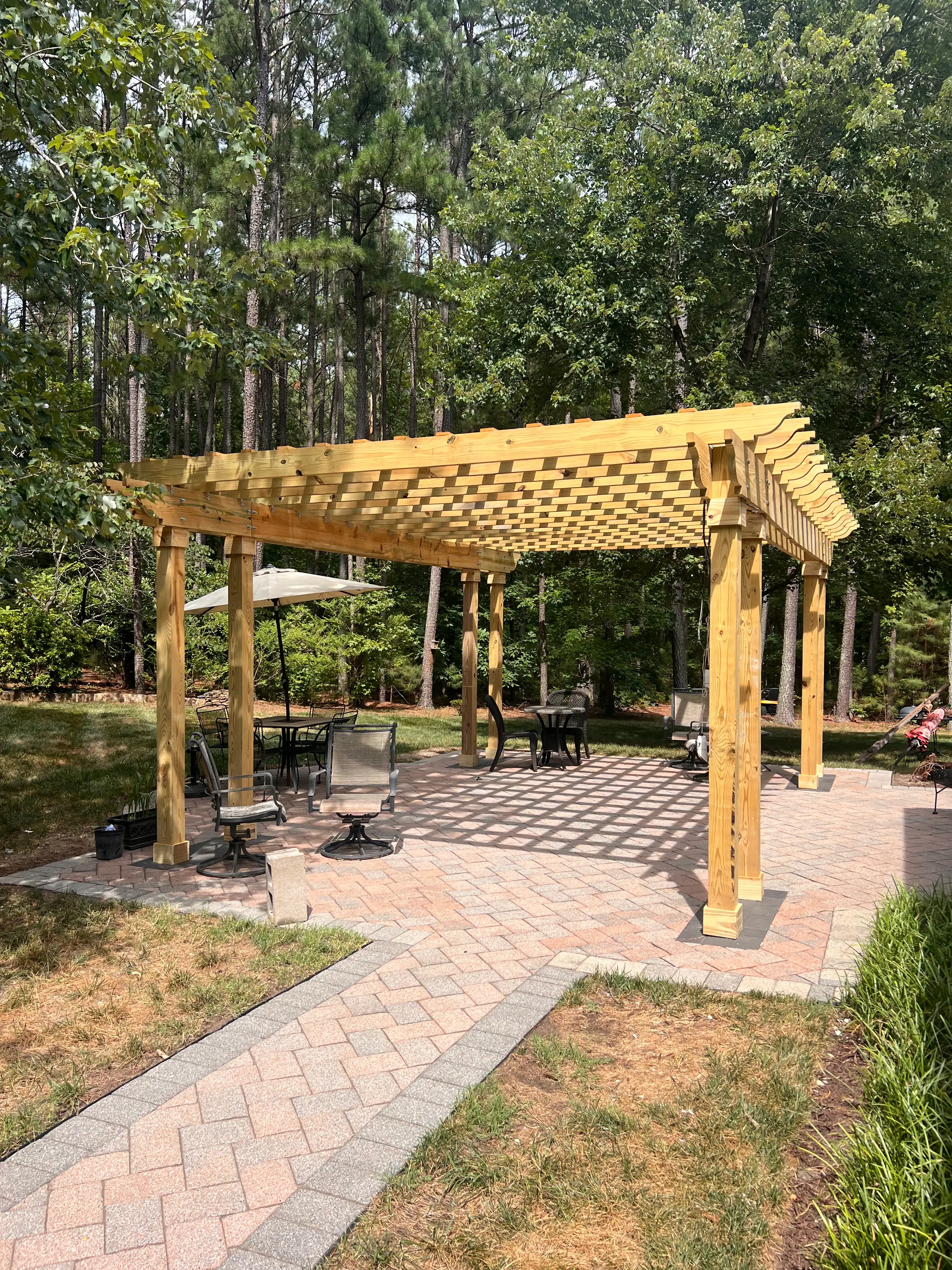 A beautiful wood pergola over a patio in the midst of a backyard