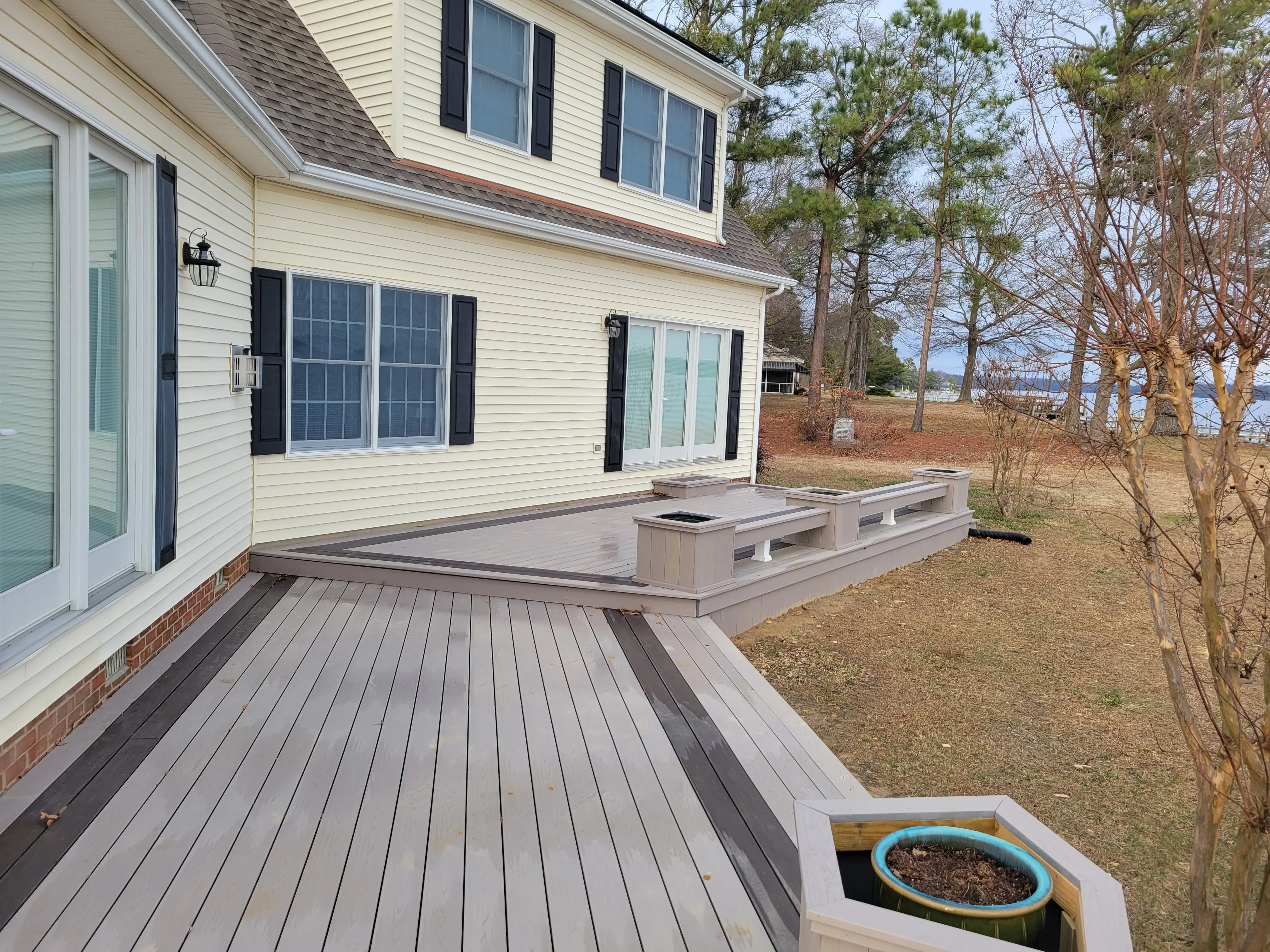 A large deck wrapping a yellow house with Timbertech Azek Harvest in Slate Gray and Timertech Azek Vintage Dark Hickory for double border