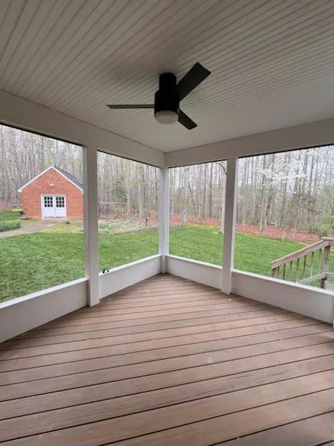 A screen porch with a deck on top