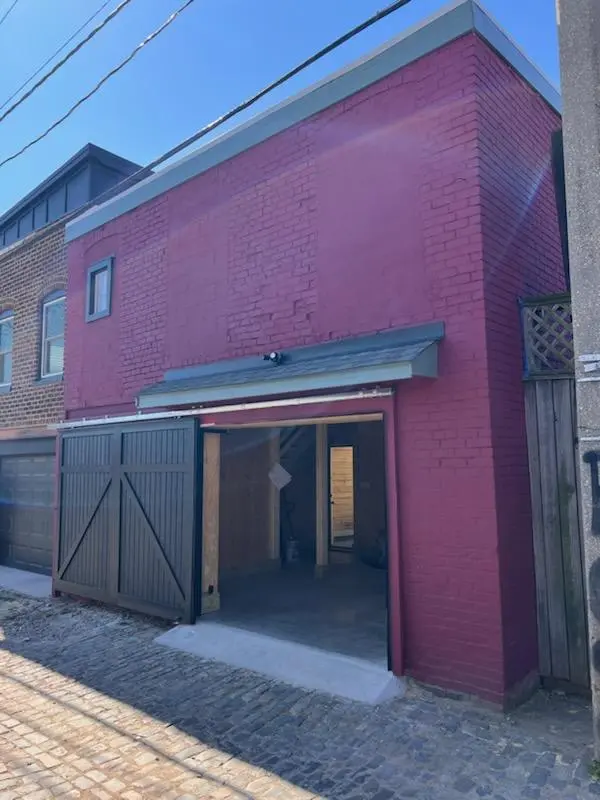 A painted red brick building with a black sliding door garage open