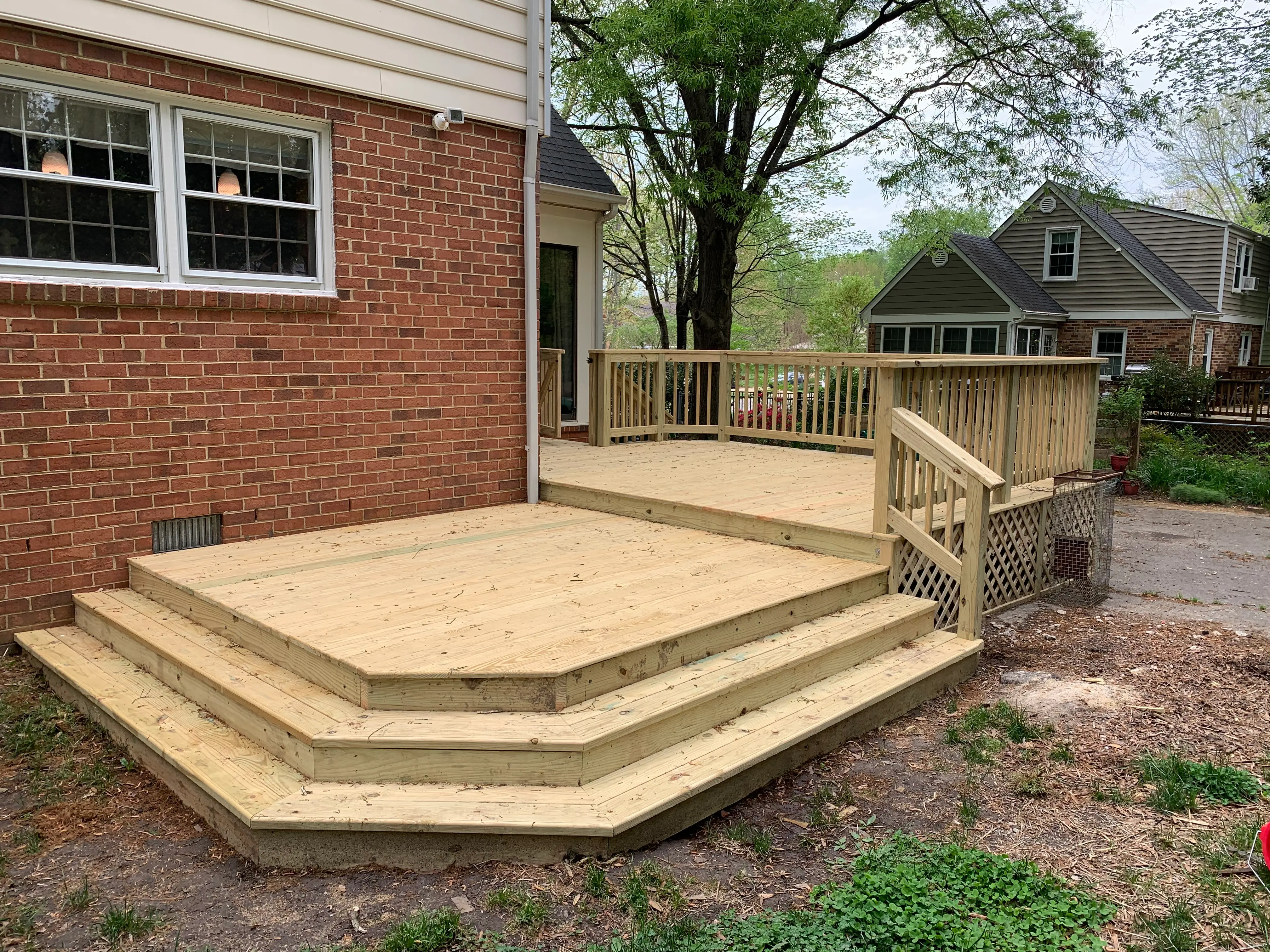 A fresh wood deck with two large platforms, crossing lattice, and two steps wrapping around the bottom platform