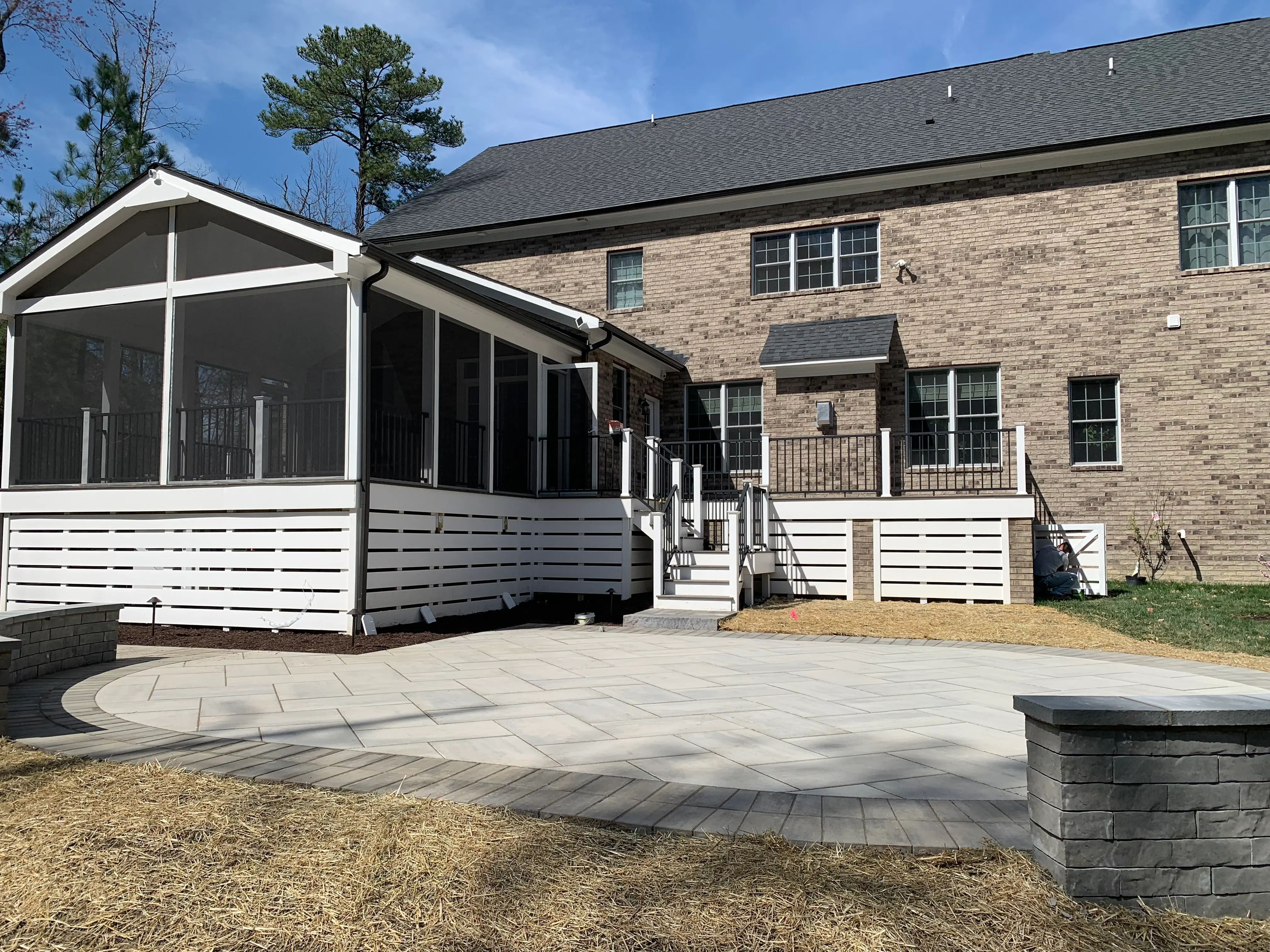 Large screen porch with deck made of Trex Coastal Bluff and stairs leading to back yard with a large stone patio