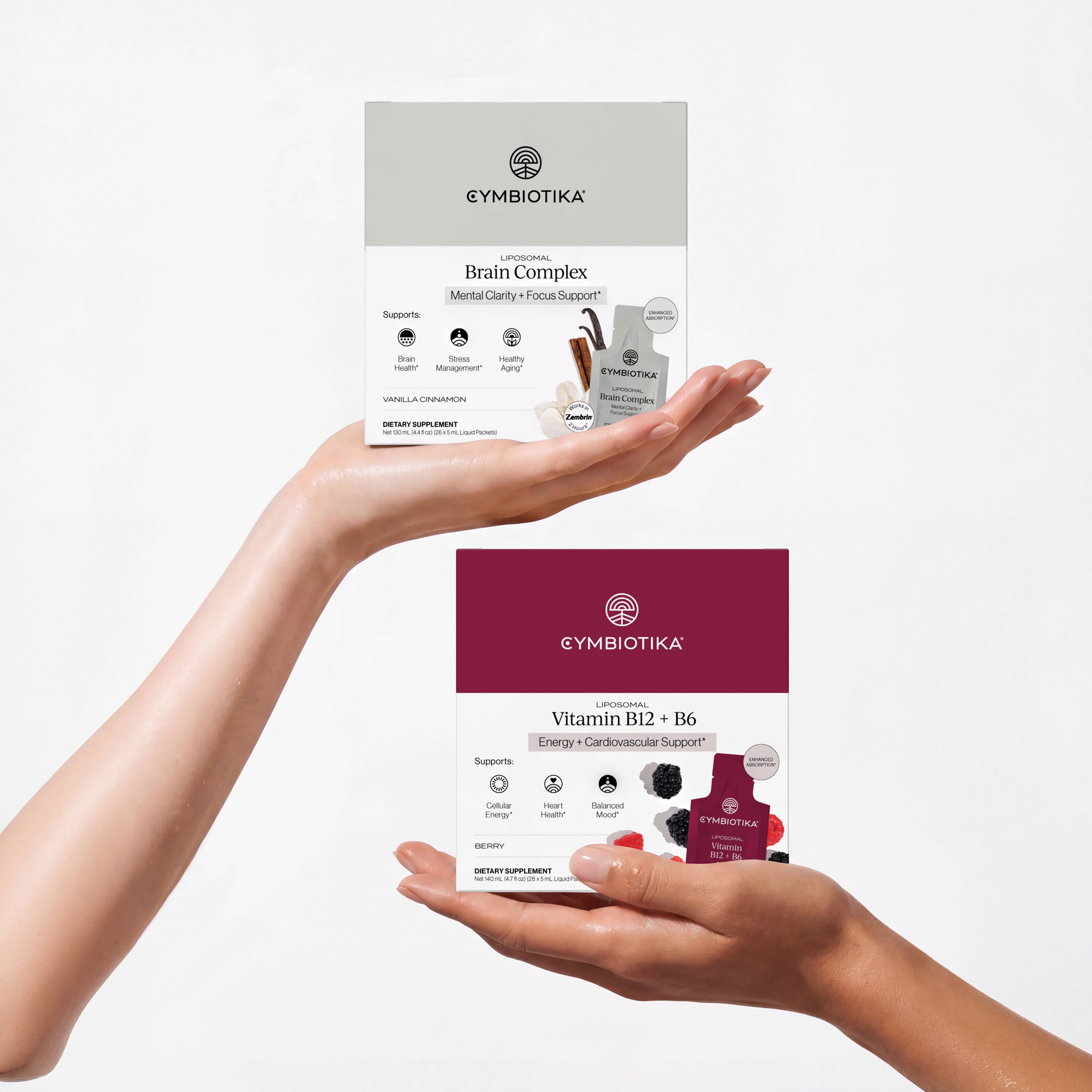 Hands present Cymbiotika Liposomal Brain Complex and Vitamin B12 + B6 boxes with matching sachets.