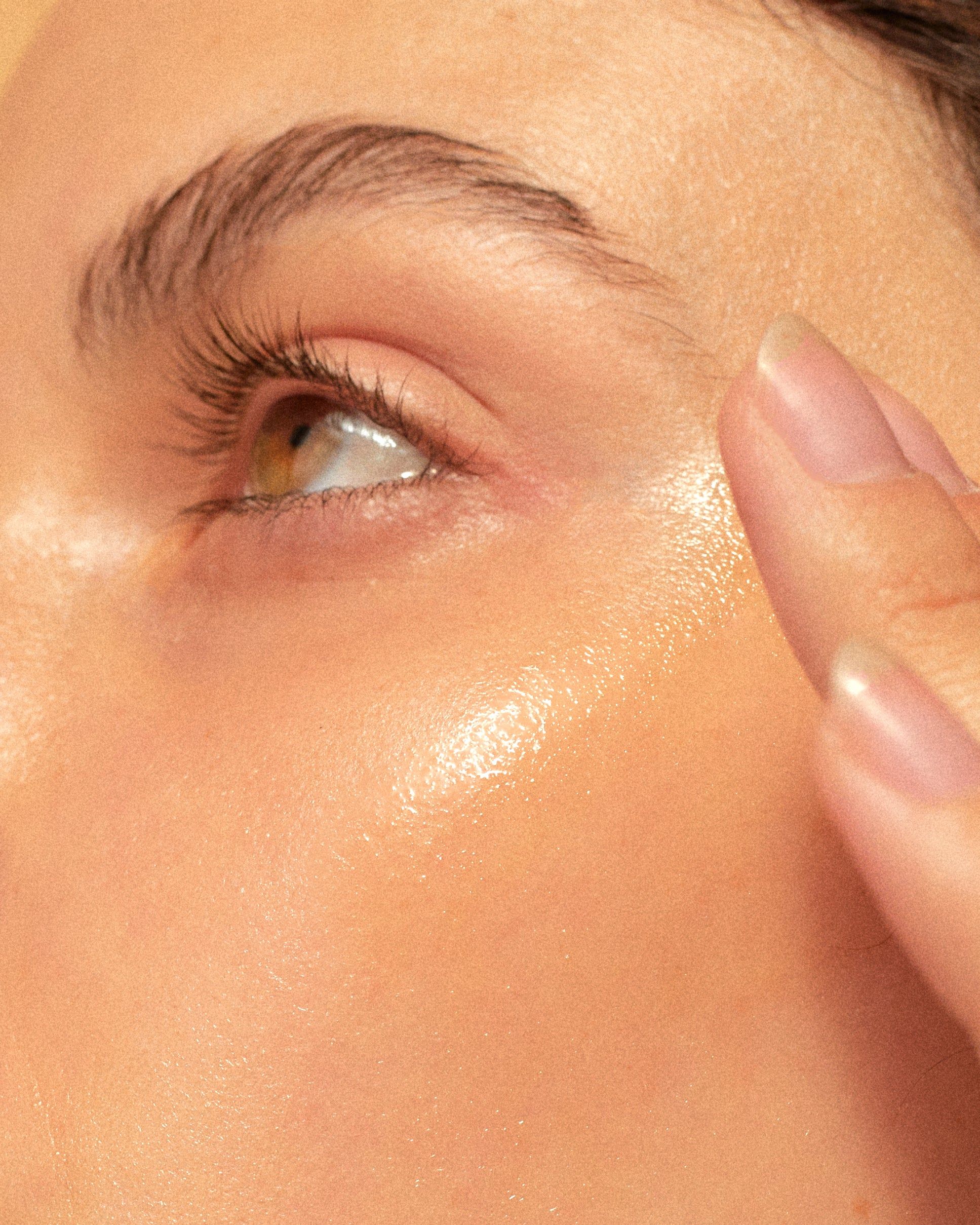 Close-up of a person's eye, cheek, and fingers touching the temple.