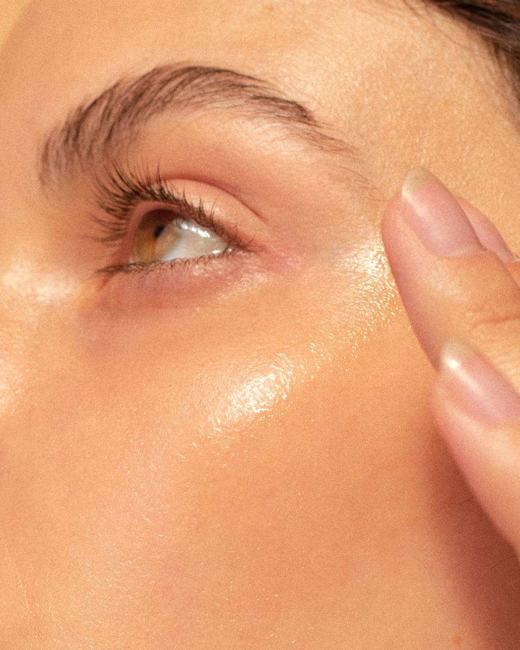 Close-up of a person's eye, cheek, and fingers touching the temple.
