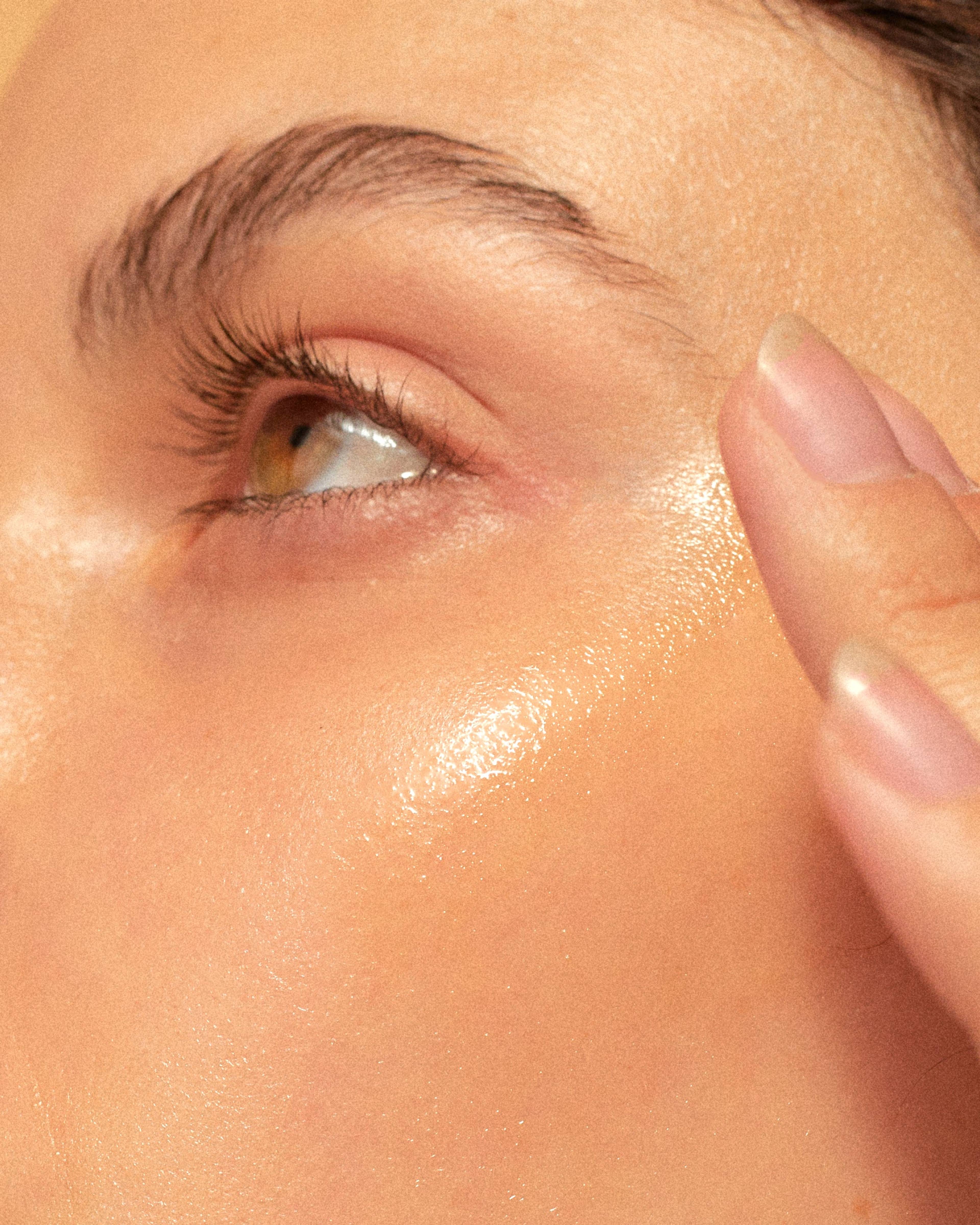Close-up of a person's eye, cheek, and fingers touching the temple.