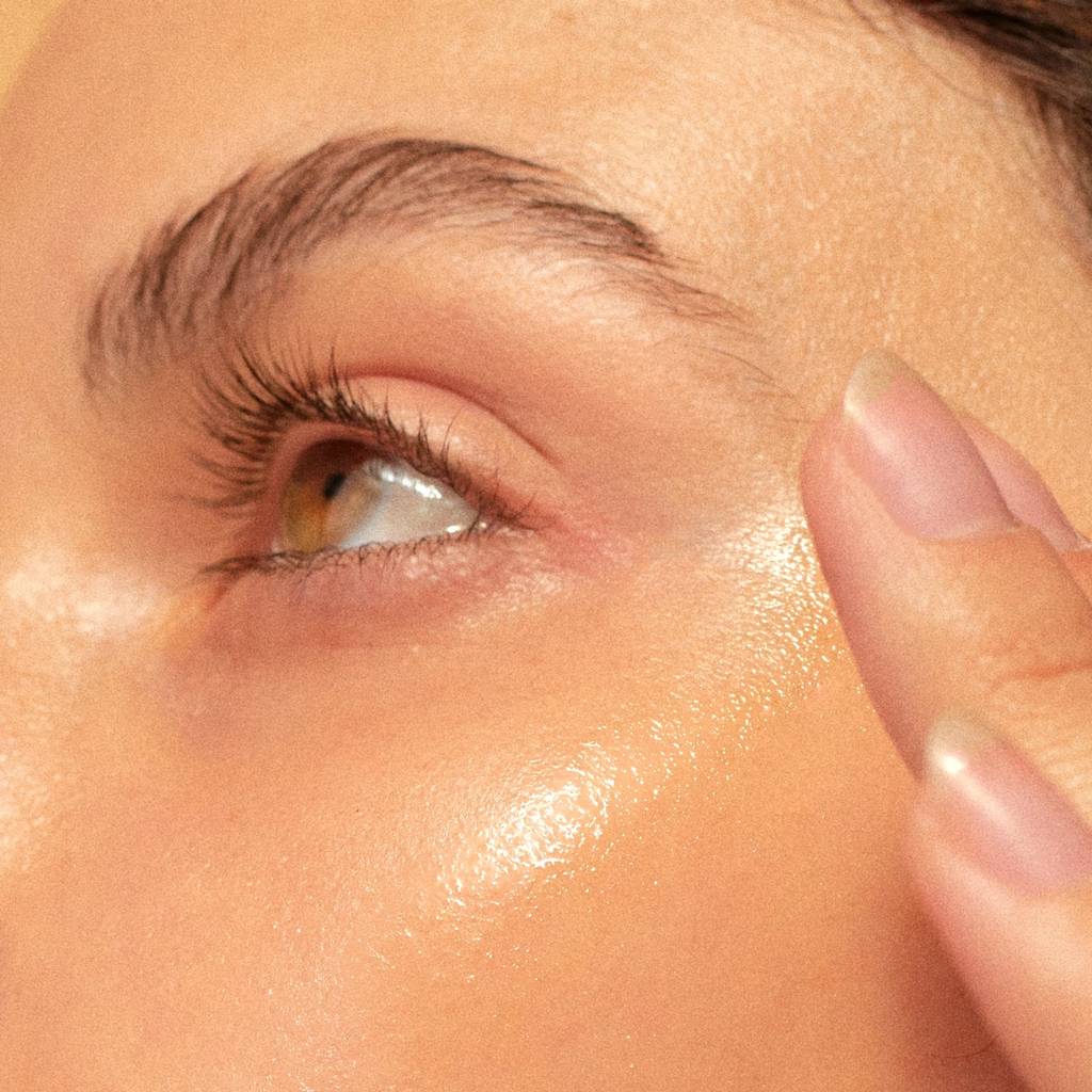Close-up of a person's eye, cheek, and fingers touching the temple.