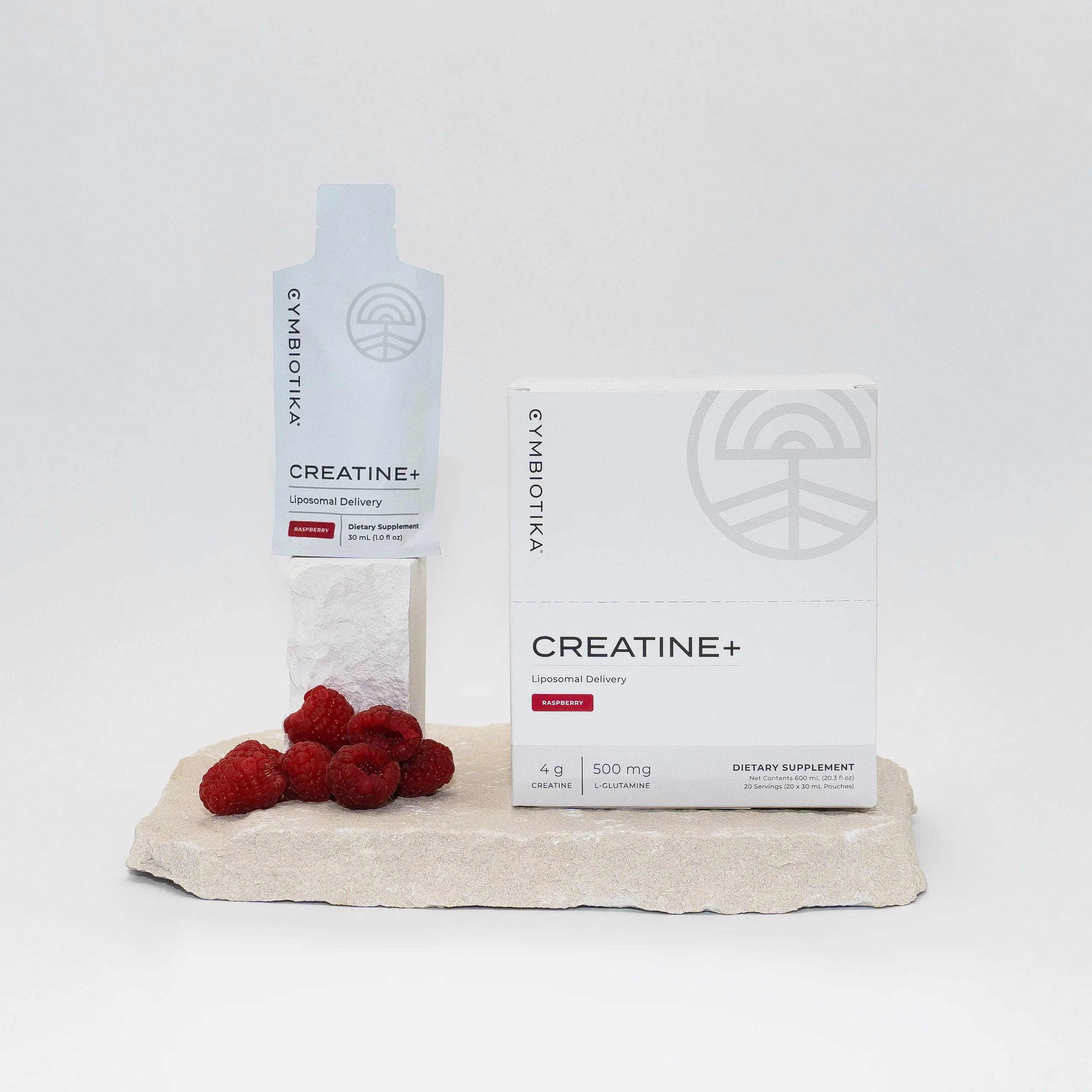 Cymbiotika Creatine+ box and single-serving packet beside fresh raspberries on a stone slab.