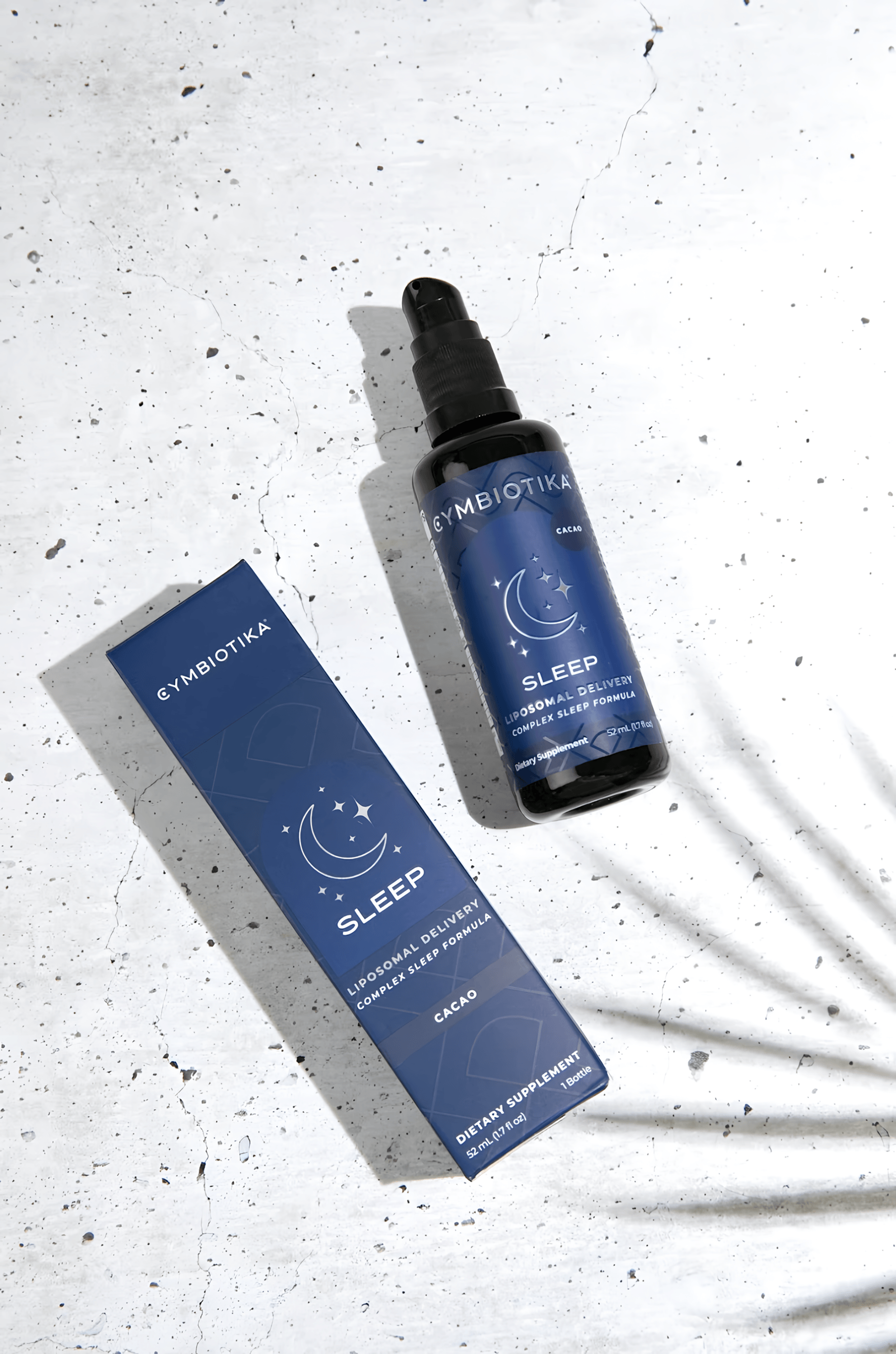Cymbiotika Liposomal Sleep cacao bottle and box on a speckled white surface.