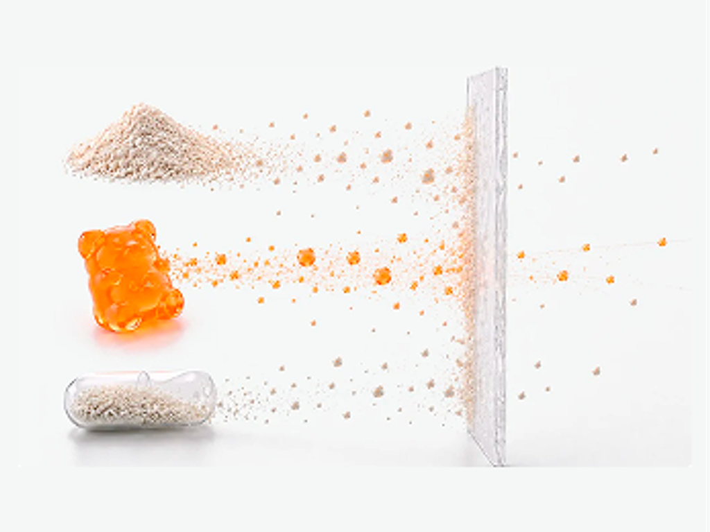 Powder, a gummy, and a capsule disperse into particles at a barrier, illustrating nutrient delivery methods.