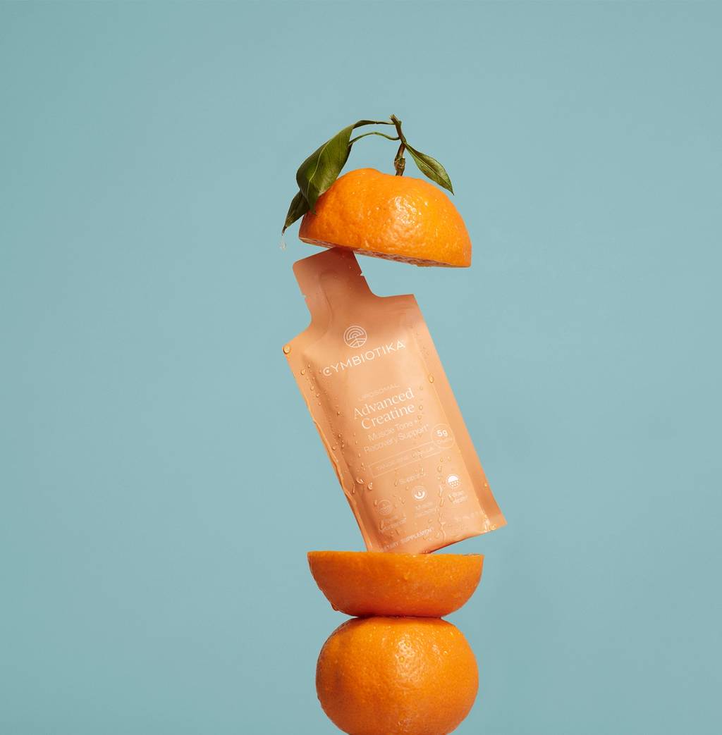 Orange Advanced Creatine sachet suspended between orange halves against a blue background.