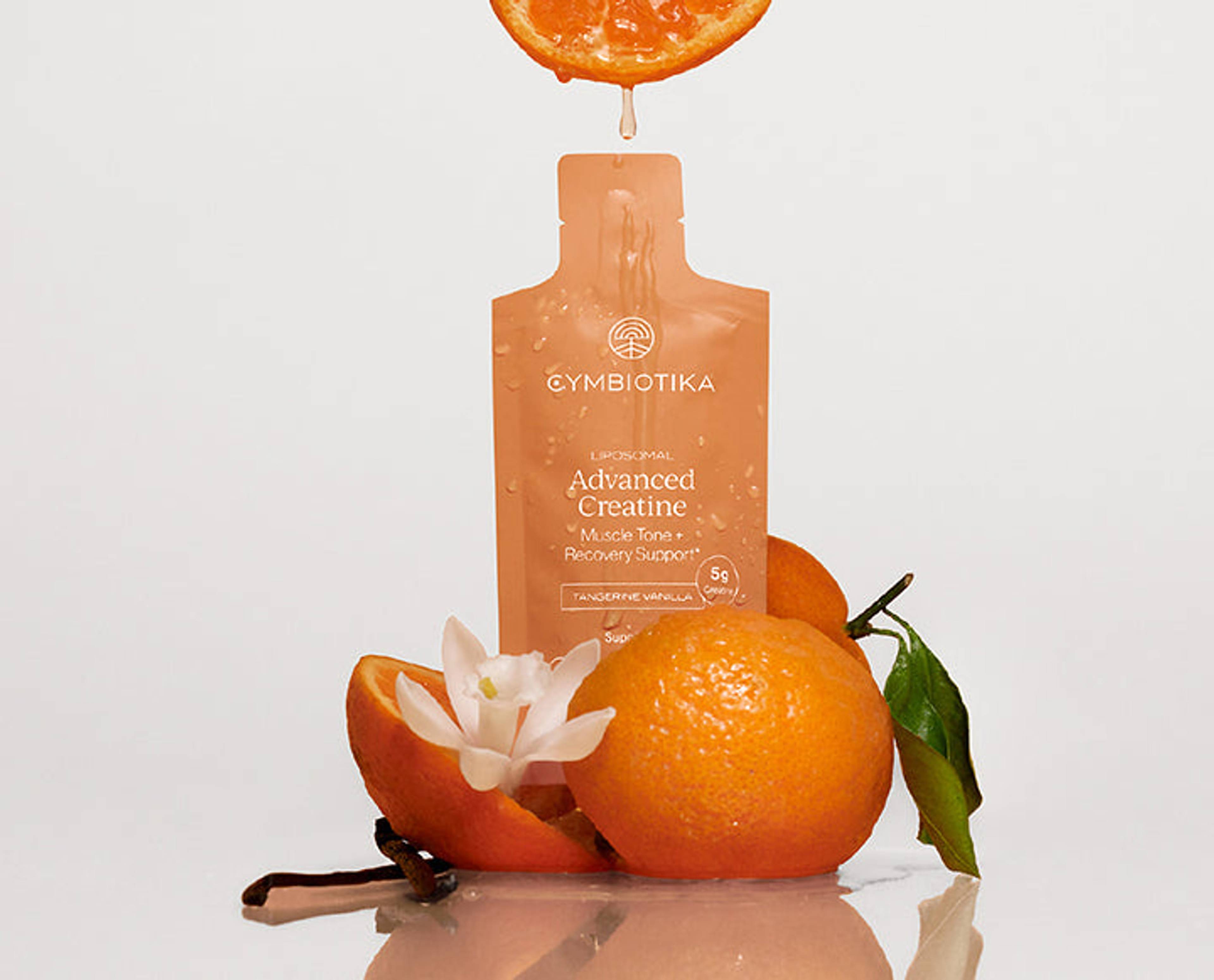 Cymbiotika Advanced Creatine sachet with oranges, a citrus slice, leaves, and white flower