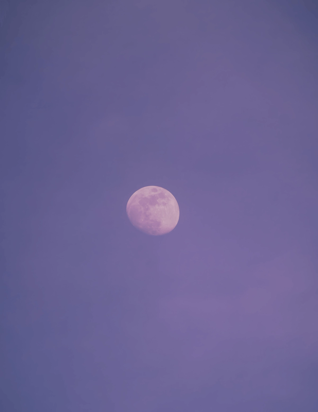 Pale full moon in a hazy purple sky.